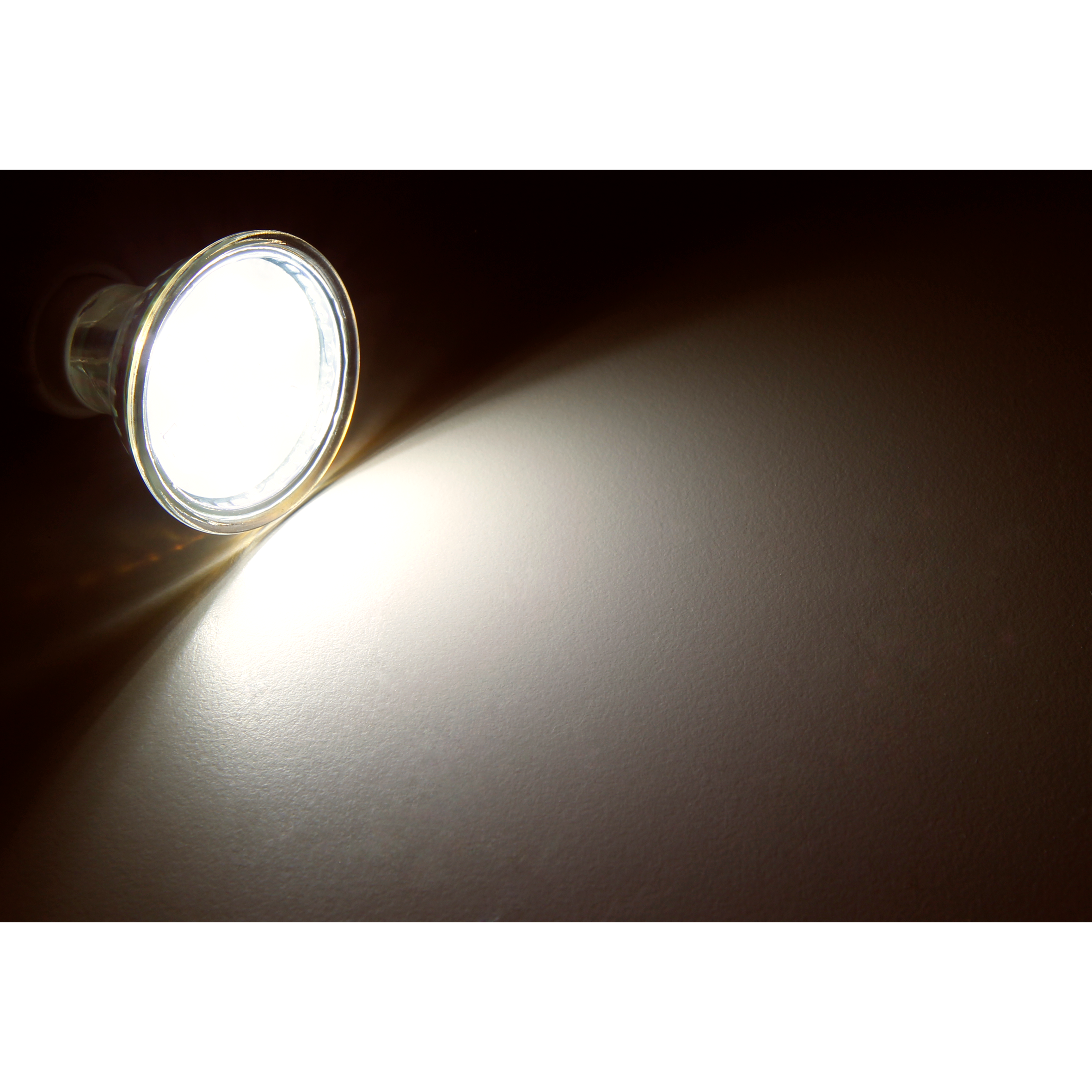 Ein Scheinwerfer, der auf eine Wand scheint. Das Licht ist hell und der Hintergrund ist dunkel.