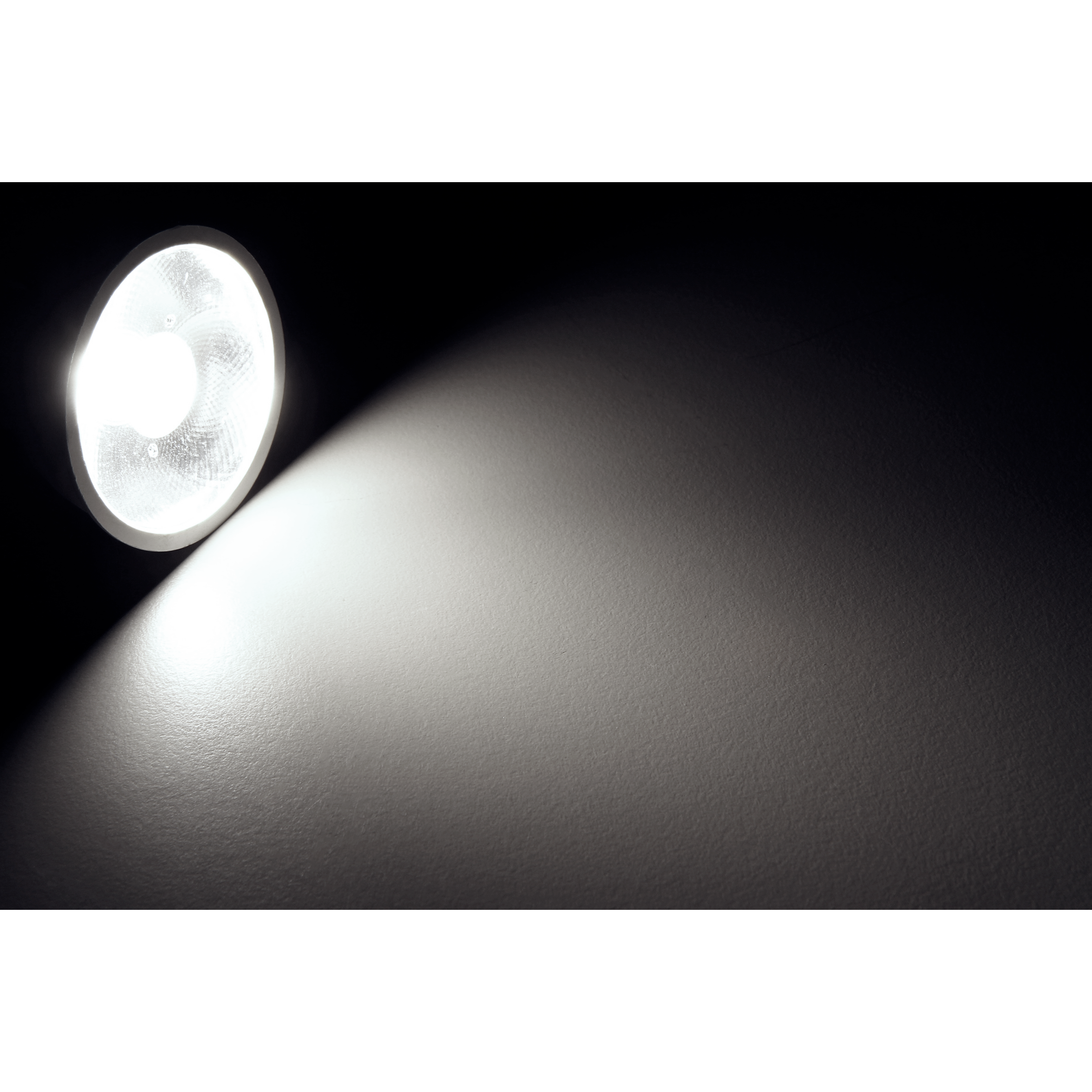 Scheinwerfer in einem dunklen Raum. Das Licht scheint auf eine weiße Wand.