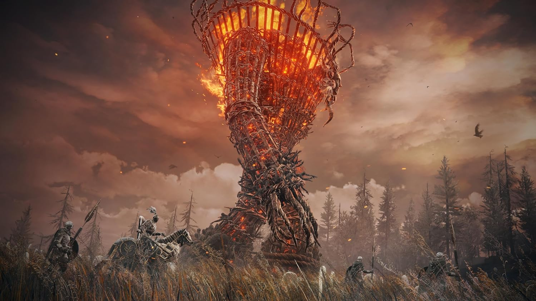 Wysoka konstrukcja z ognia na polu, postacie na pierwszym planie, ciemne niebo.