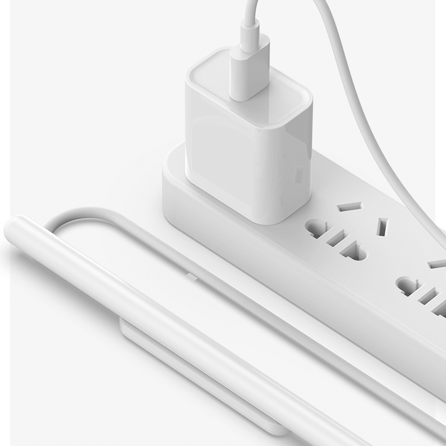 Weiße Steckdosenleiste mit eingestecktem weißen Netzteil. Ein Kabel führt davon weg.