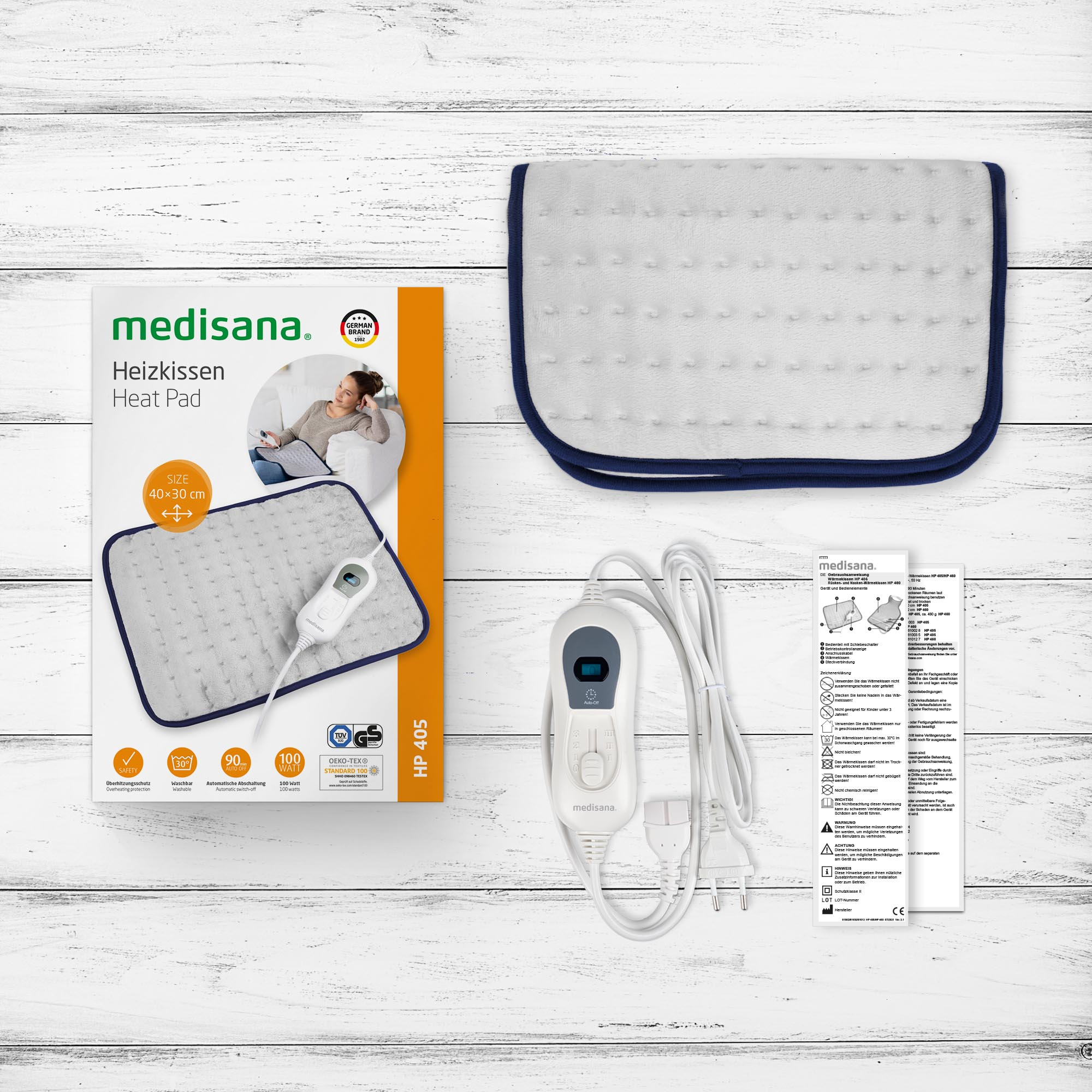 Poduszka grzewcza i opakowanie na jasnym drewnianym stole. Pudełko pokazuje produkt i szczegóły.