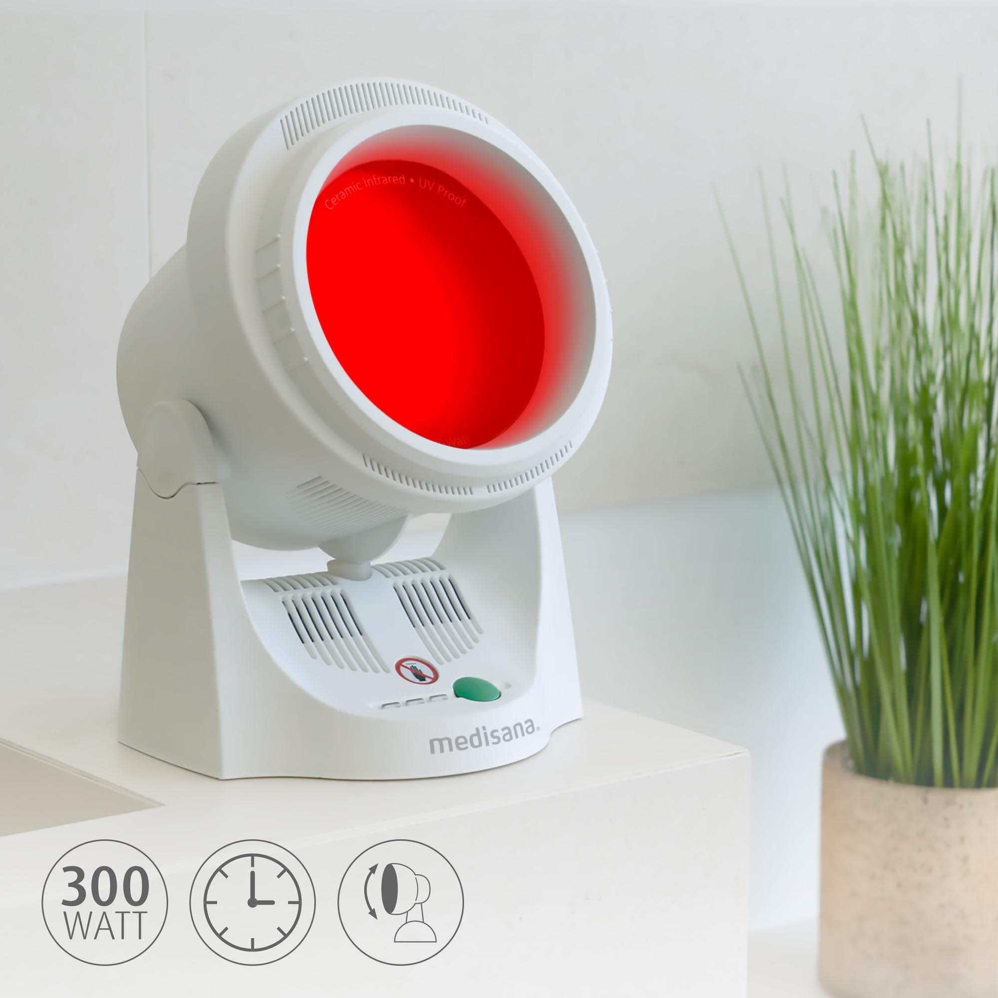 Lampe infrarouge blanche avec lueur rouge, un bouton vert et une petite plante en pot sur une surface blanche.