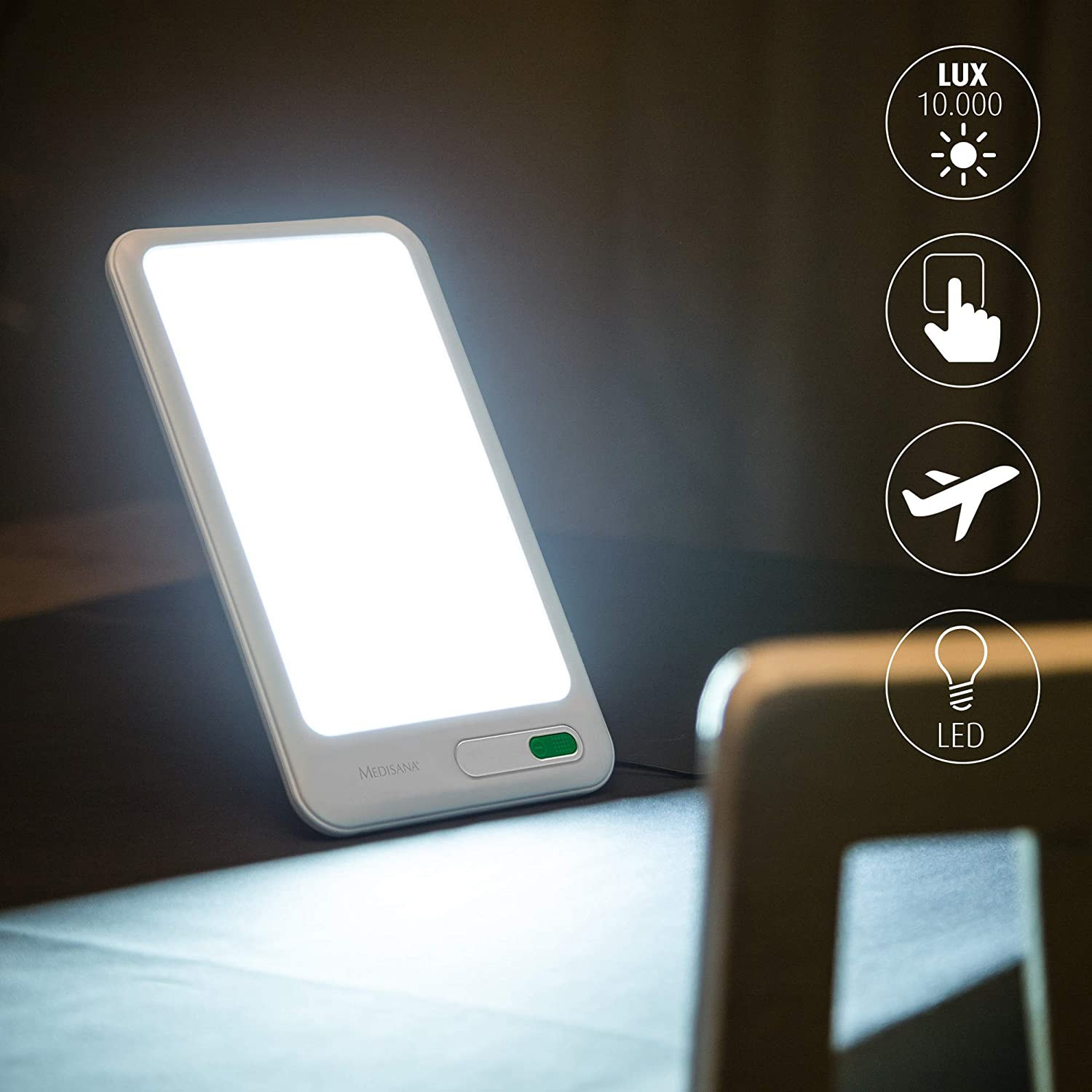 Biała lampa do terapii z zielonym przyciskiem, ze światłem włączonym. Ikony obok, czarne tło.