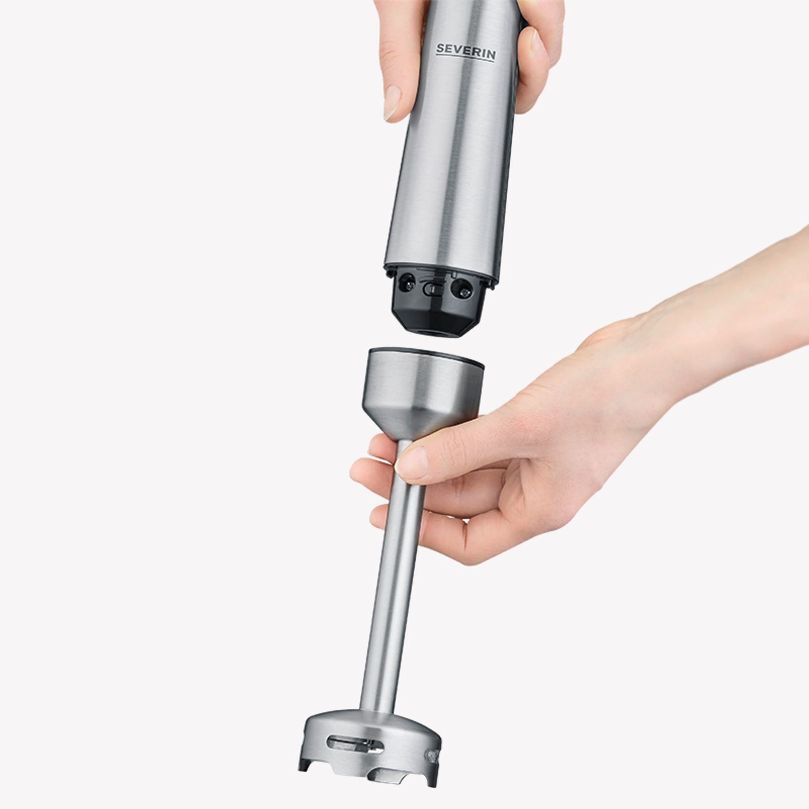 A person's hands assembling a silver blender. The parts are being connected.