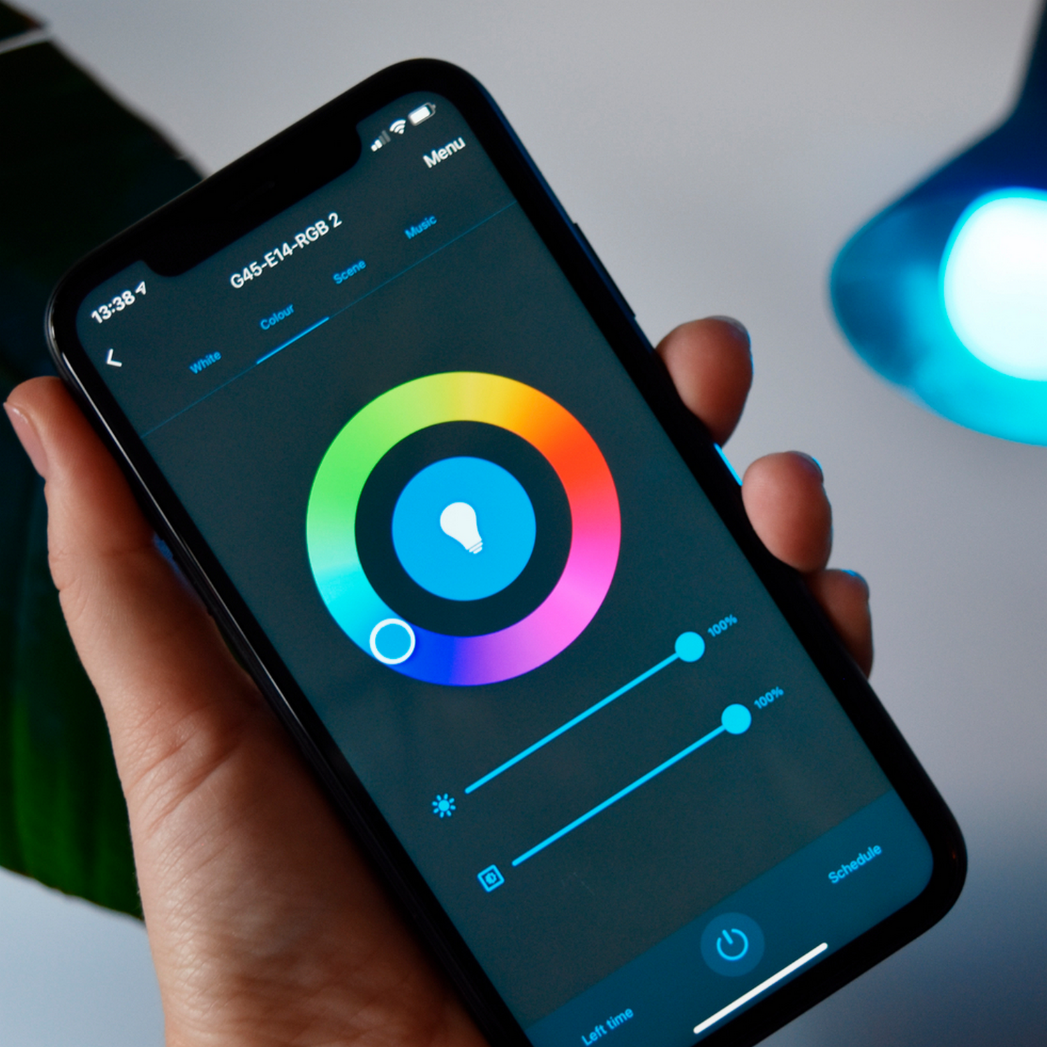 Una mano che tiene uno smartphone che mostra una ruota dei colori per controllare una luce intelligente.