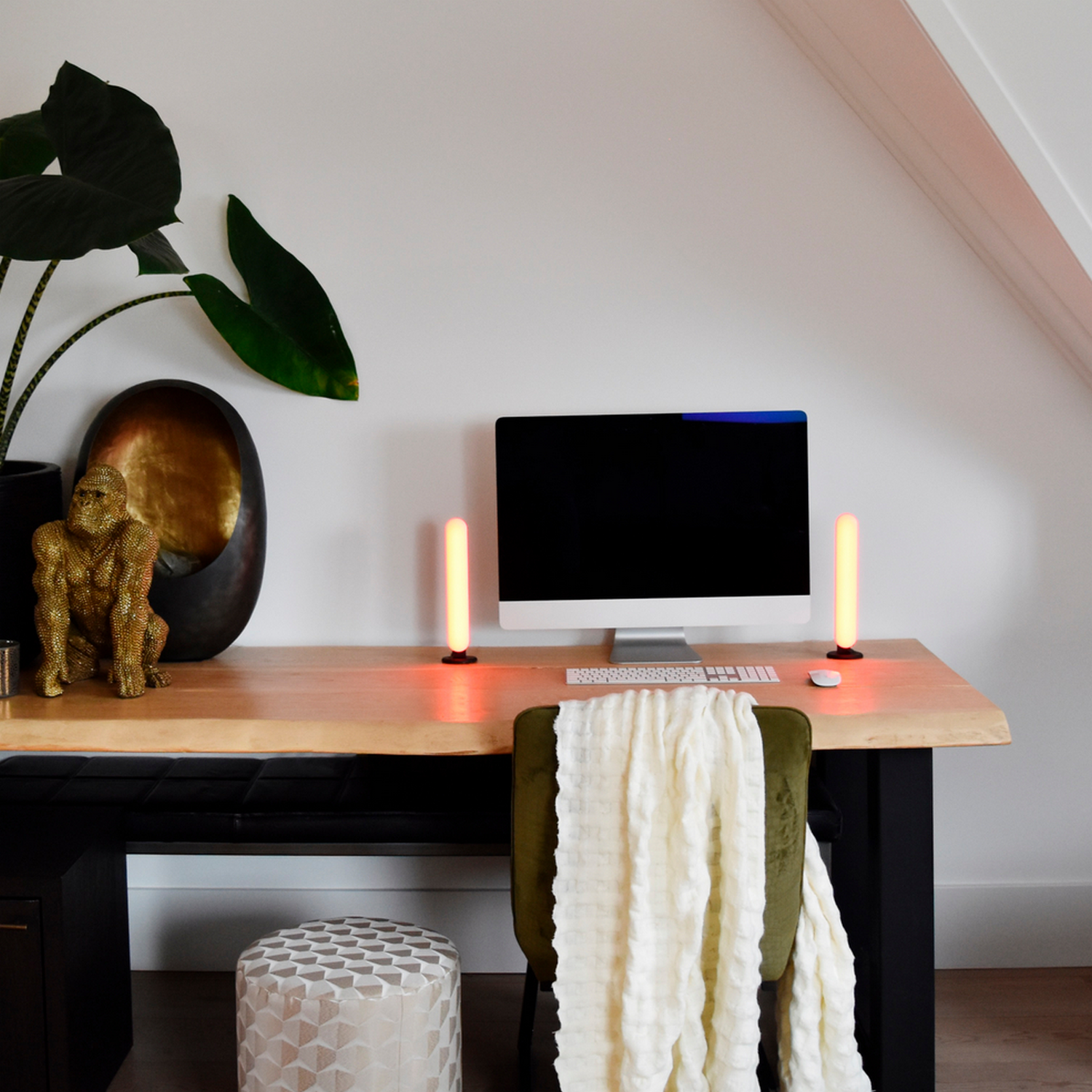 Spazio di lavoro con scrivania, computer e lampade, con piante e oggetti decorativi.