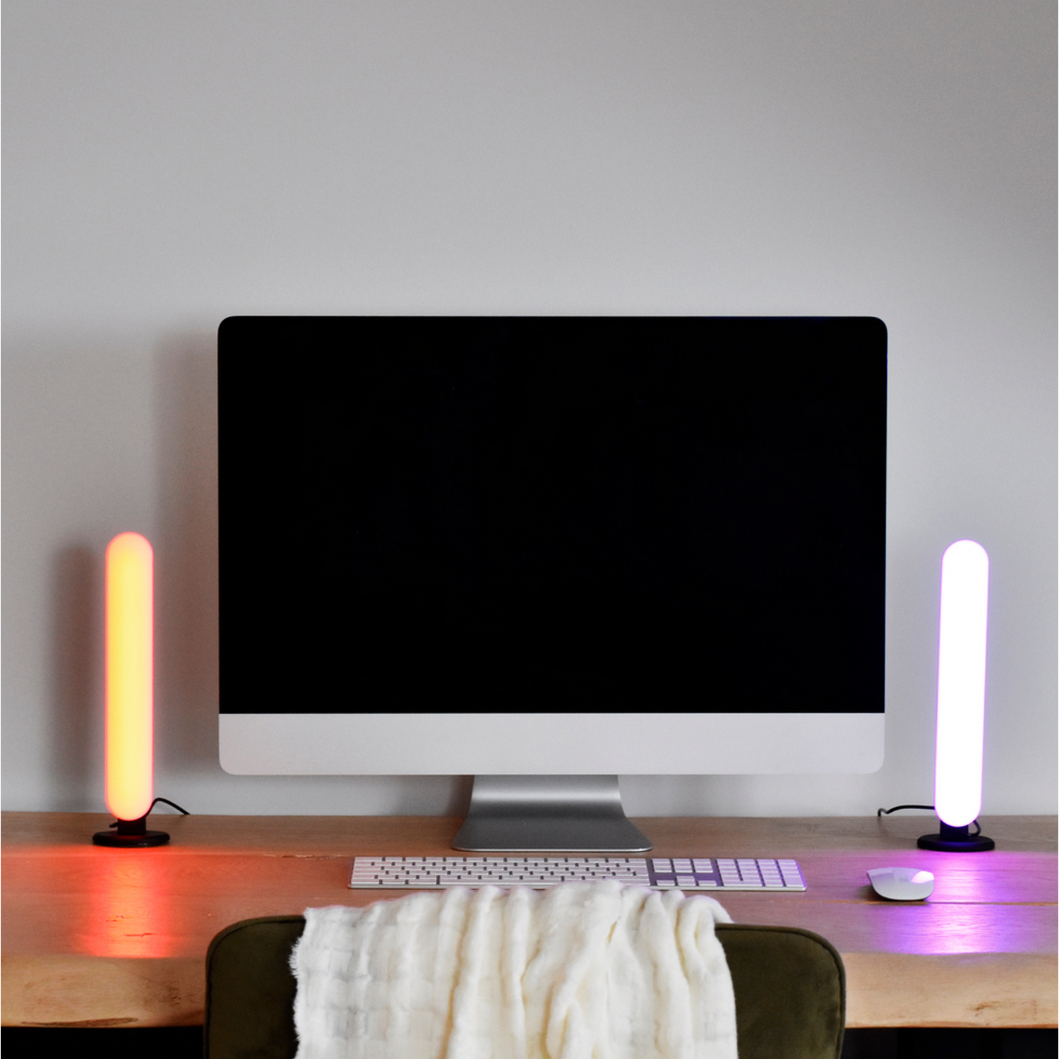 Schermo del computer con due barre luminose. Tastiera e mouse bianchi sulla scrivania.