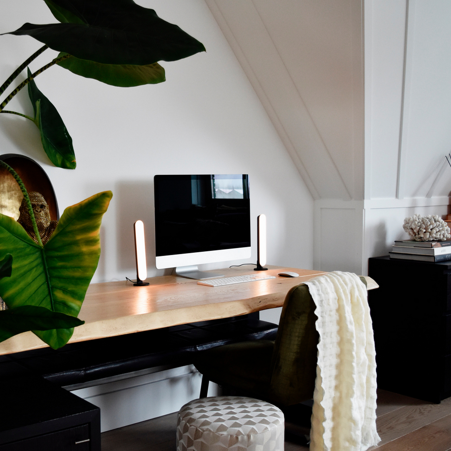 Scrivania moderna per ufficio domestico con computer, lampade e decorazioni.