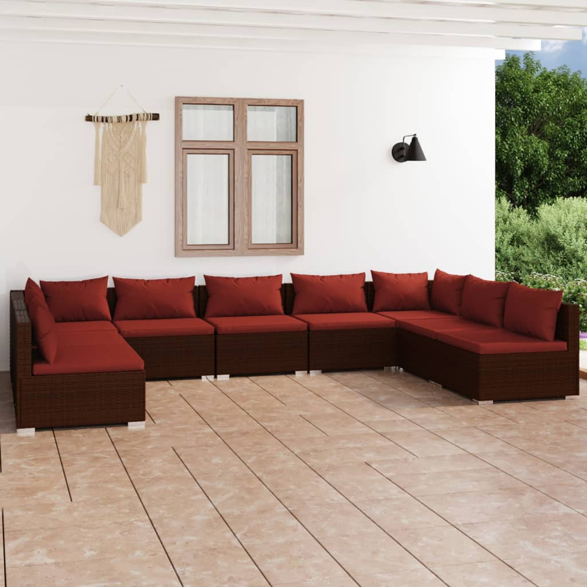 Terrassenmöbel-Set im Freien mit einem braunen Ecksofa und roten Kissen. Auf einer gefliesten Terrasse mit weißer Wand.