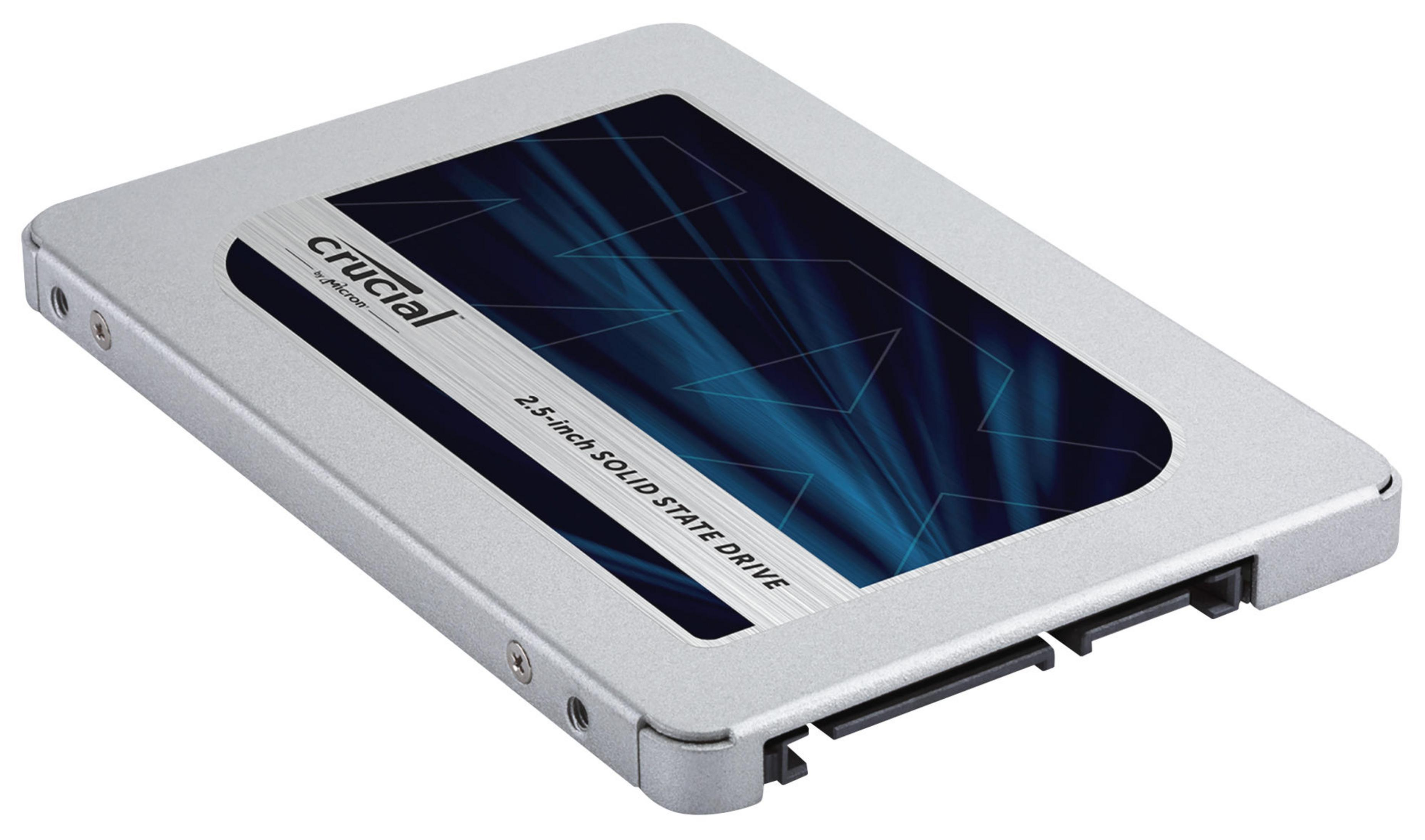 SSD Crucial de 2,5 pulgadas plateada con etiqueta azul y blanca, en ángulo sobre superficie blanca.