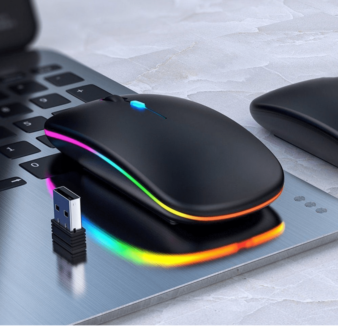 Eine schwarze kabellose Maus mit bunten LED-Lichtern, USB-Empfänger und Laptop-Tastatur.