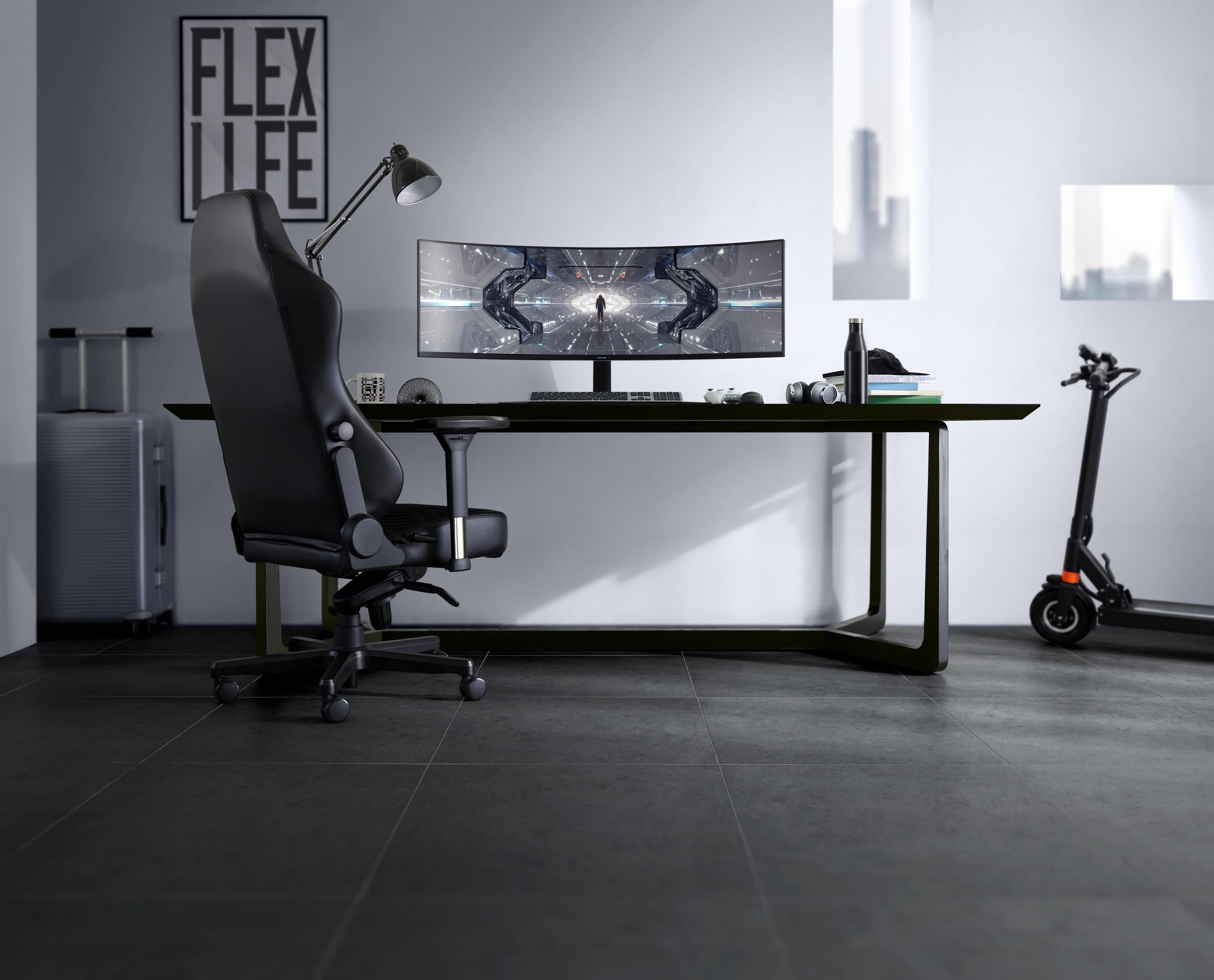 Un moderno spazio di lavoro con un monitor curvo, sedia e scooter.
