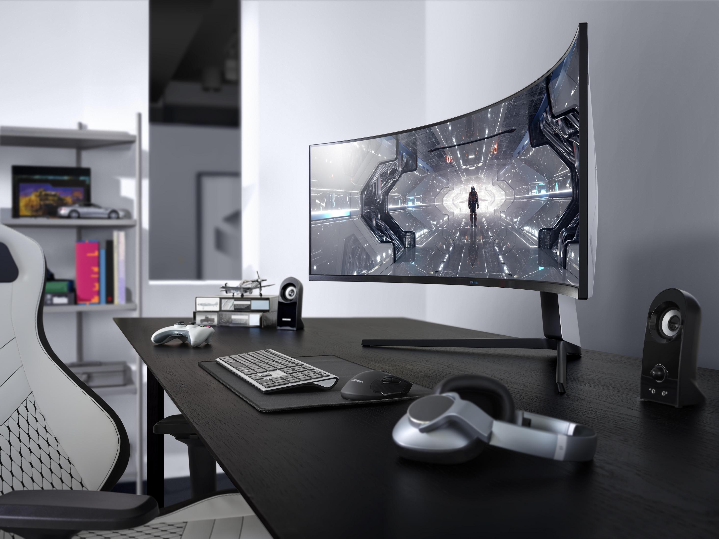 Monitor curvo da gioco su una scrivania con periferiche in una stanza.
