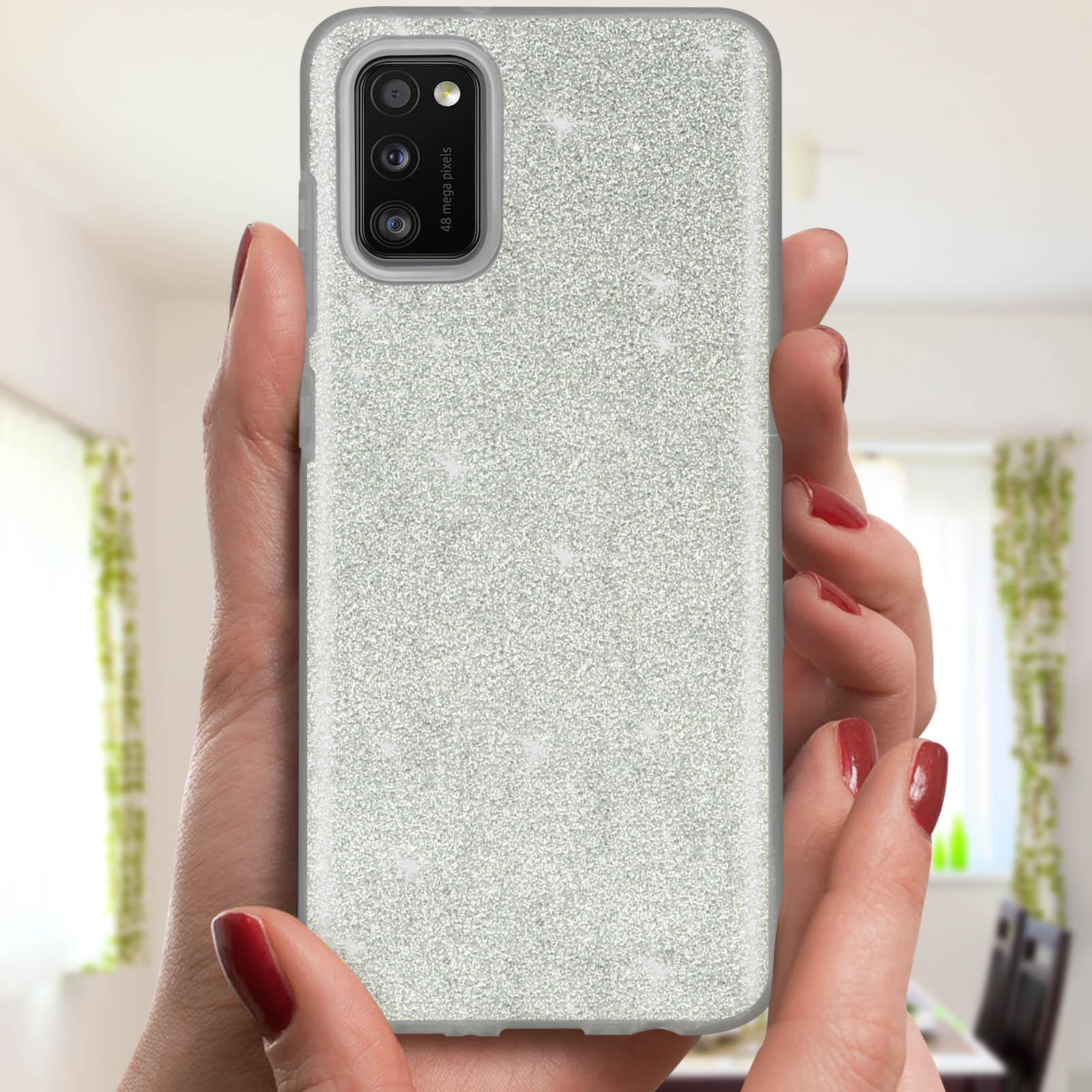 Vrouwenhanden die een telefoonhoes vasthouden bedekt met glitter. Rode nagellak.