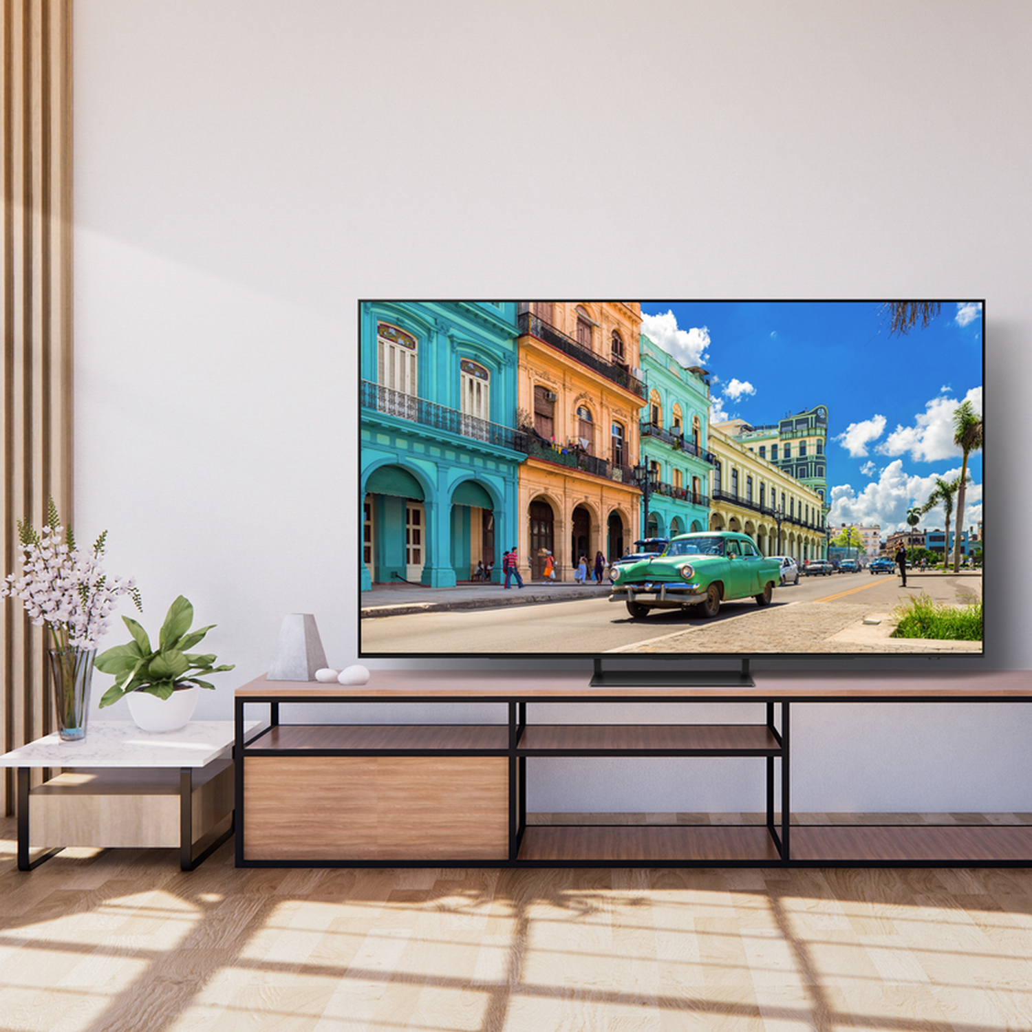 Telewizor pokazujący scenę uliczną na Kubie, ustawiony na stojaku w salonie z drewnianą podłogą.