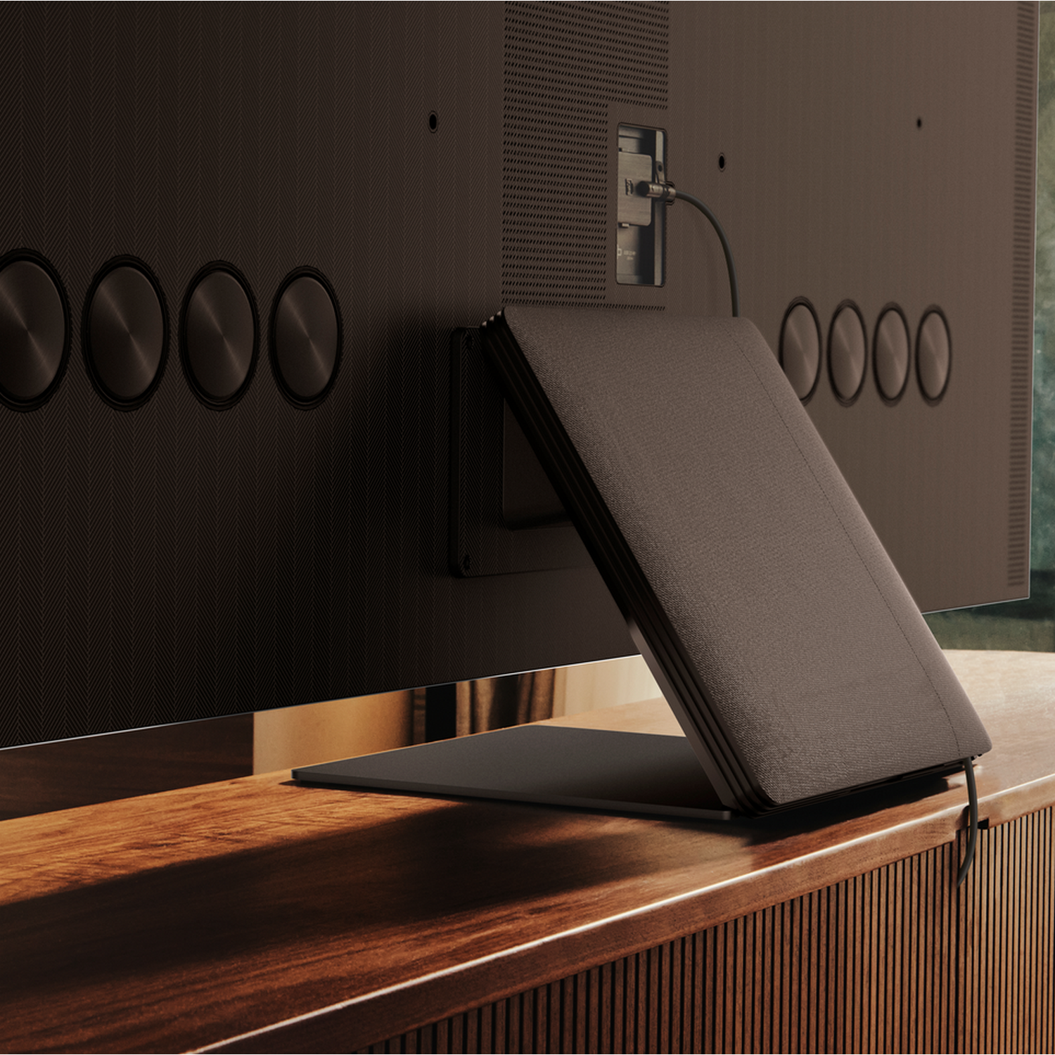 Tył ciemnobrązowego telewizora ze złożoną skórzaną osłoną na drewnianej szafce.