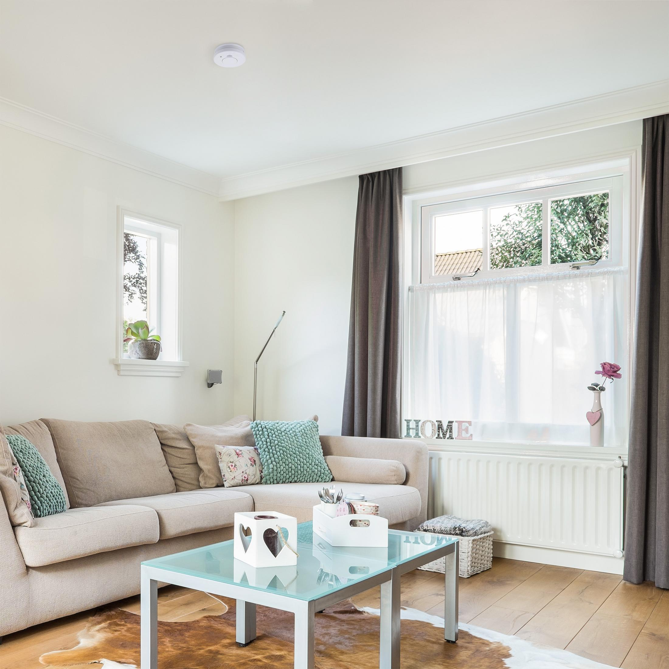 Salon z sofą, stolikiem kawowym i czujnikiem dymu na suficie.