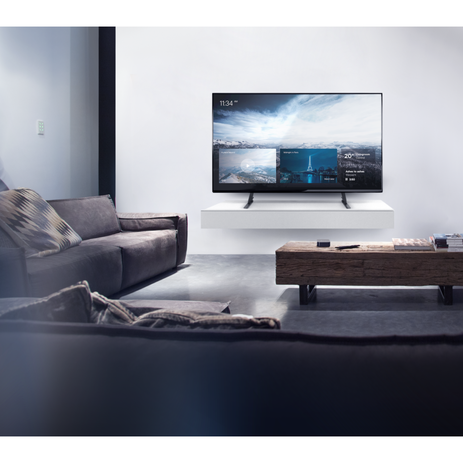 Wohnzimmer mit TV an der Wand. Sofa, Tisch und Dekoration im Blick. TV zeigt Bilder.