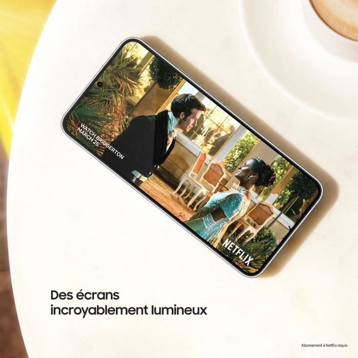 Telefon wyświetla scenę z Bridgerton. Stół na pierwszym planie. Tekst brzmi 'Des écrans incroyablement lumineux'.