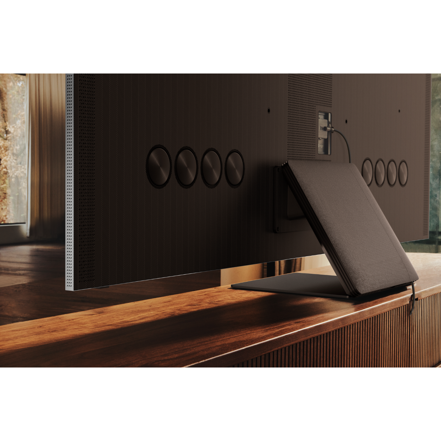 Tył czarnego telewizora na drewnianym stojaku. Ma okrągłe elementy designu i podstawkę.