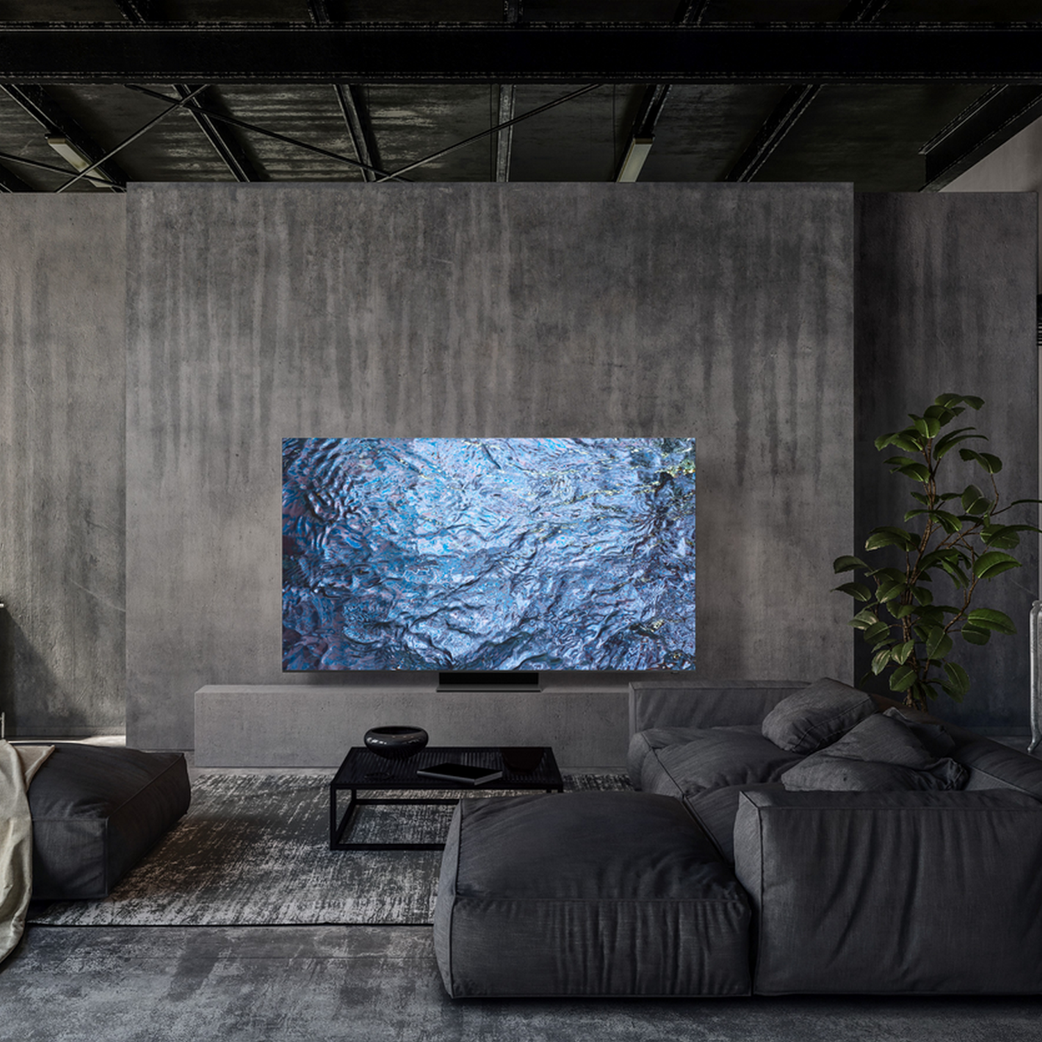 Duży telewizor wyświetla niebieskie zmarszczki wody w szarym pokoju. Szara sofa i czarny stół z przodu.