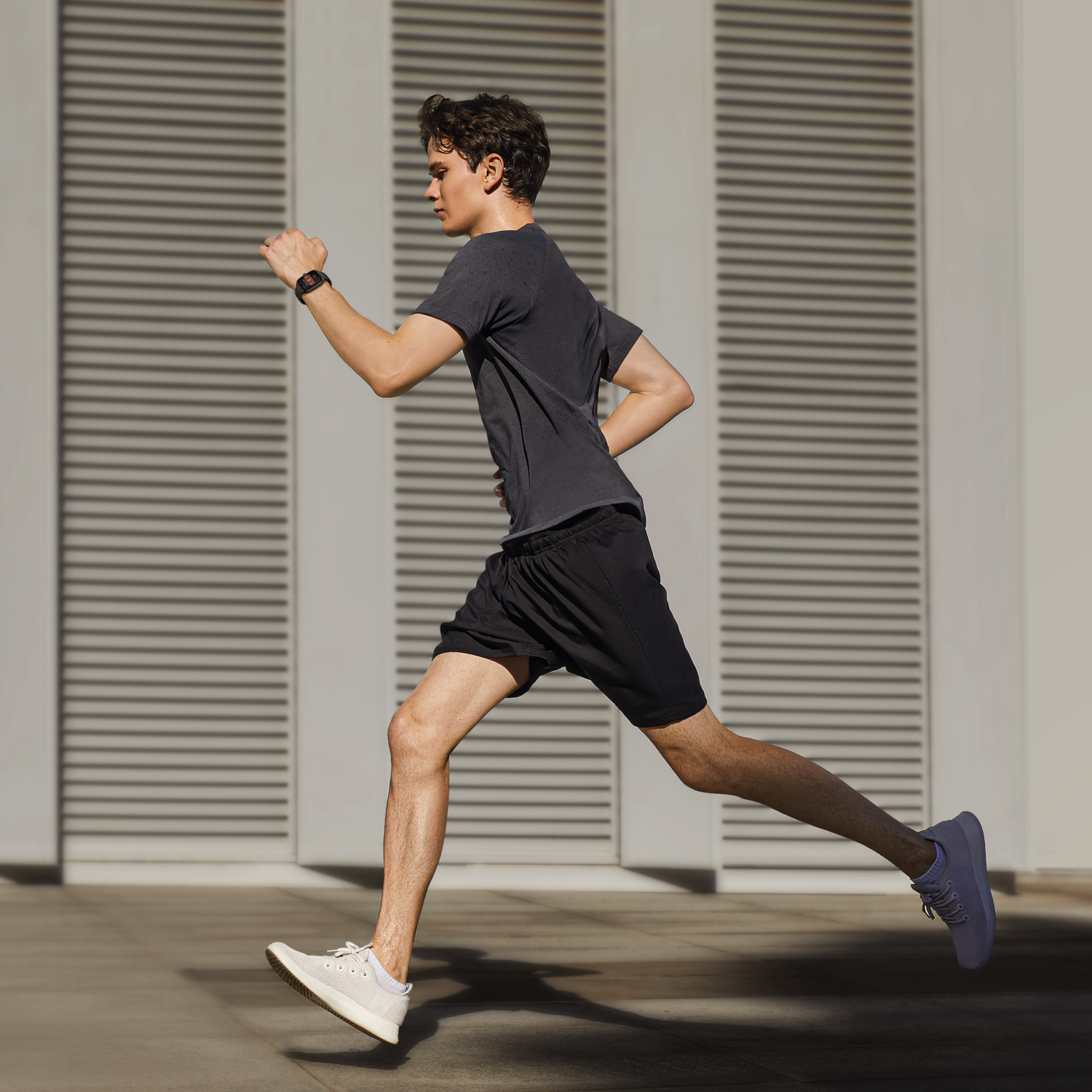 Un uomo che corre in un parco, indossa uno smartwatch e abbigliamento sportivo.