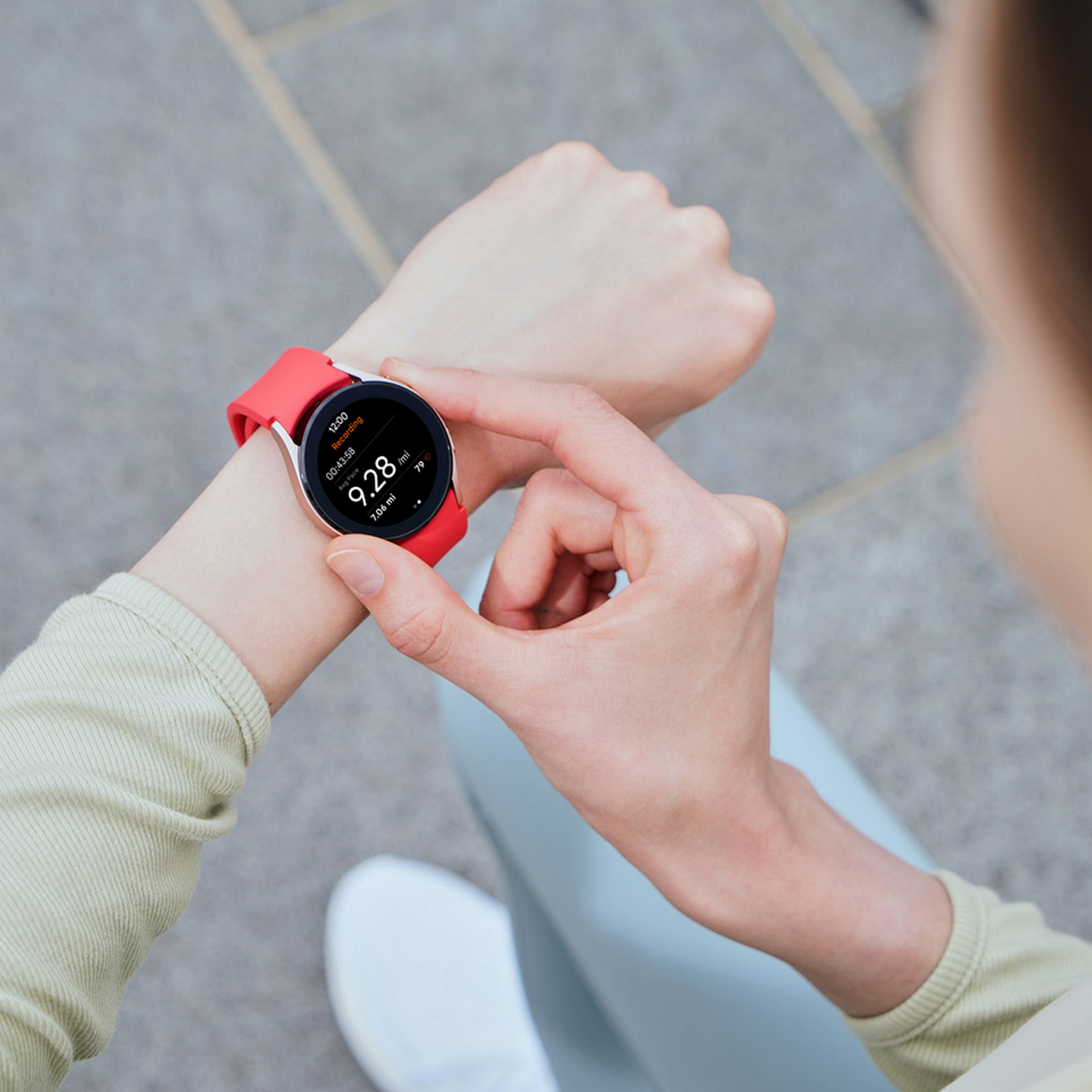 Frau trägt rote Smartwatch, Handgelenk zeigt Daten, Nahaufnahme.