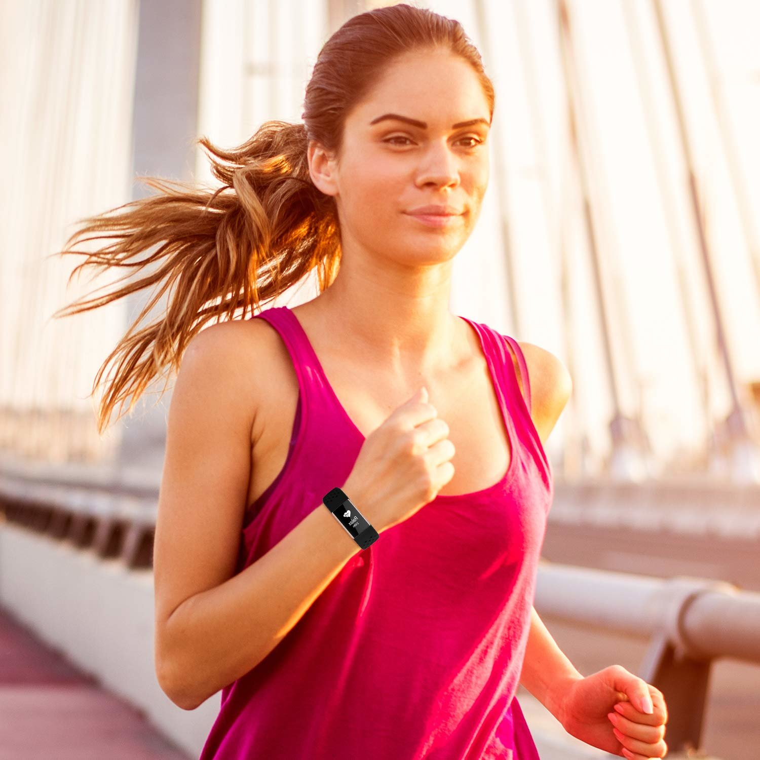 Eine Frau in einem pinken Tanktop rennt auf einer Brücke und trägt einen schwarzen Fitnesstracker.