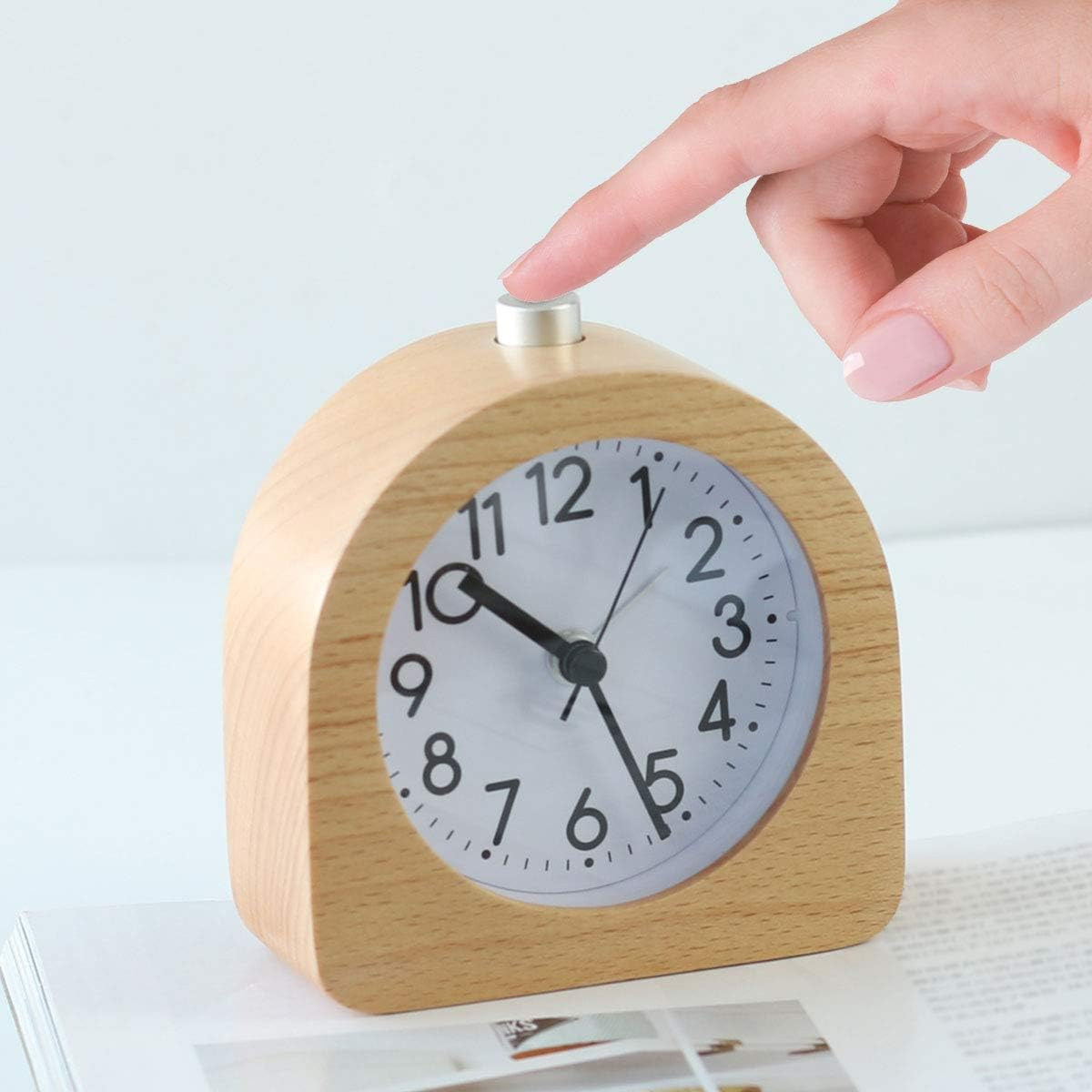 Holz-Wecker, mit einer Hand, die den oberen Knopf drückt.