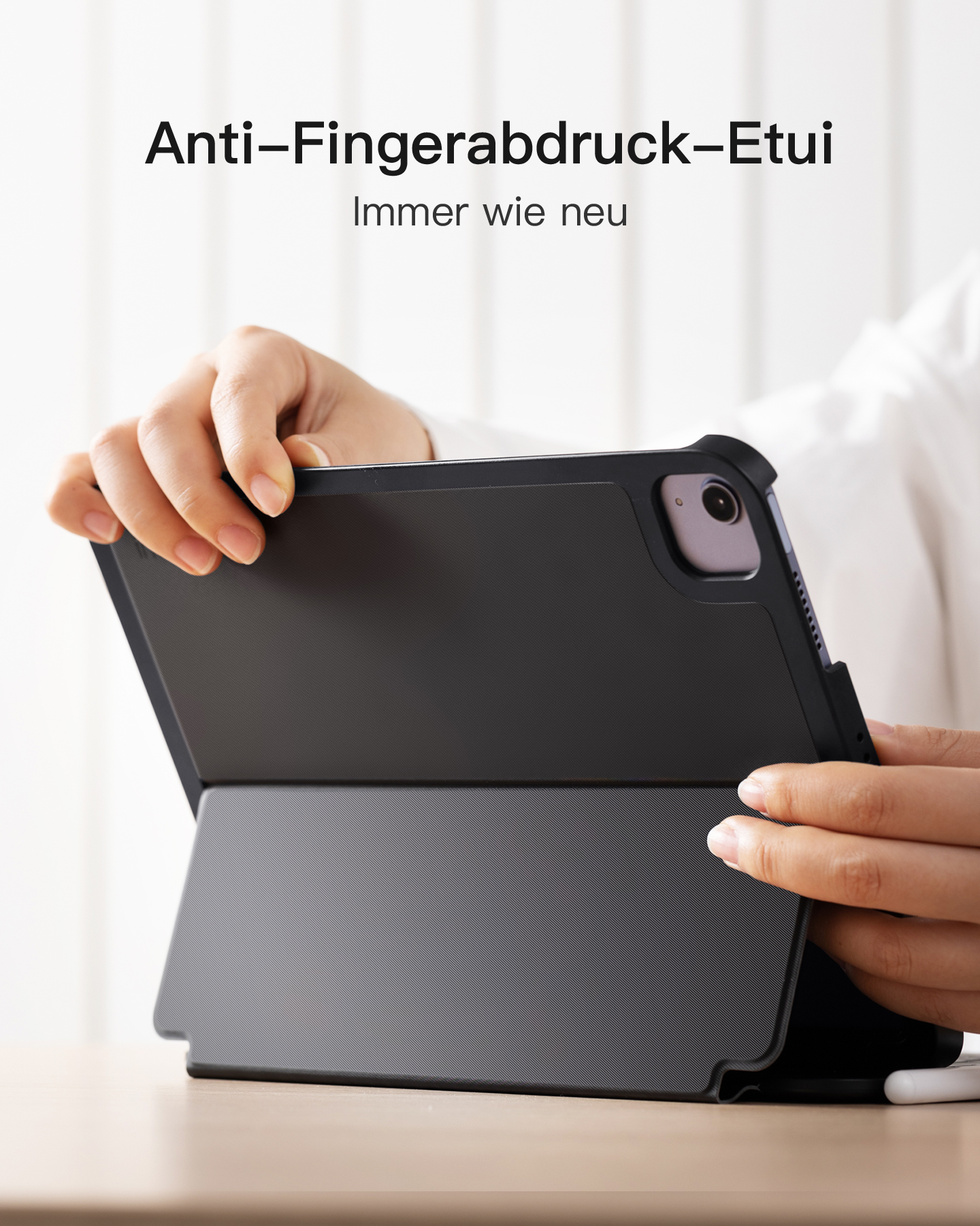 Eine Person hält eine schwarze Tablethülle mit geöffnetem Deckel auf weißem Hintergrund.