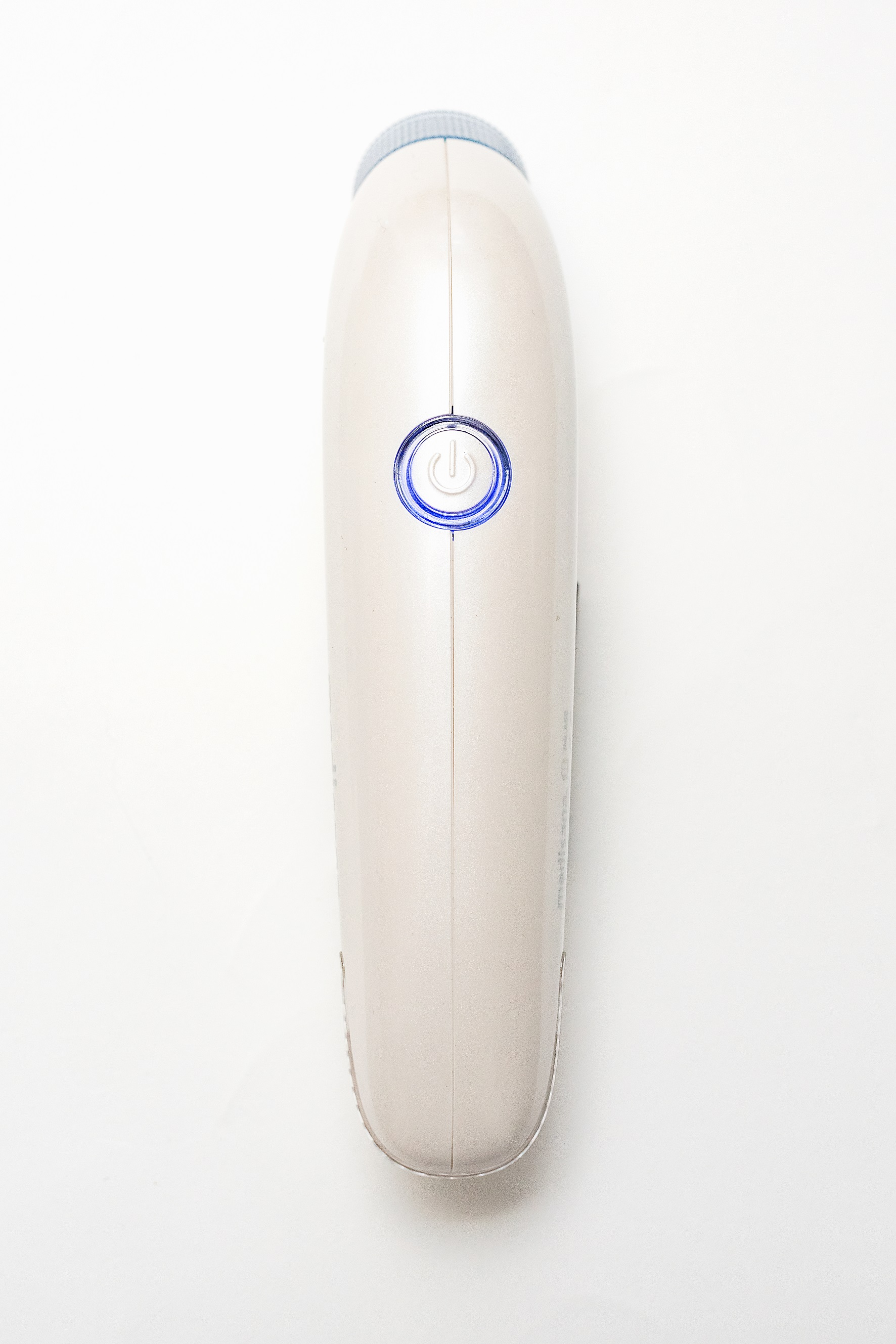 Afeitadora eléctrica beige. Vista superior, botón de encendido iluminado con luz azul.