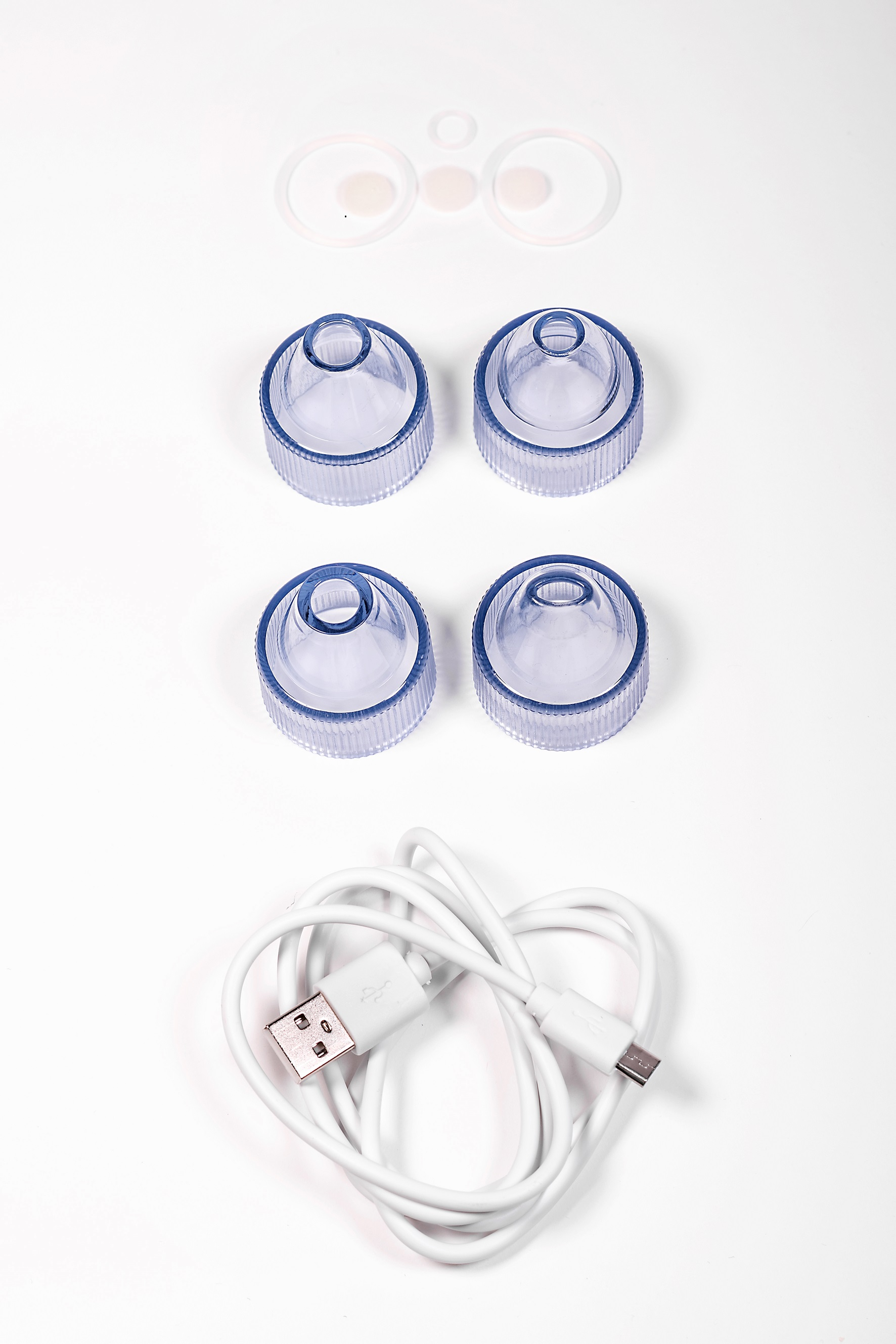 Accesorios blancos sobre un fondo blanco. Incluye ventosas azules y un cable de carga blanco.