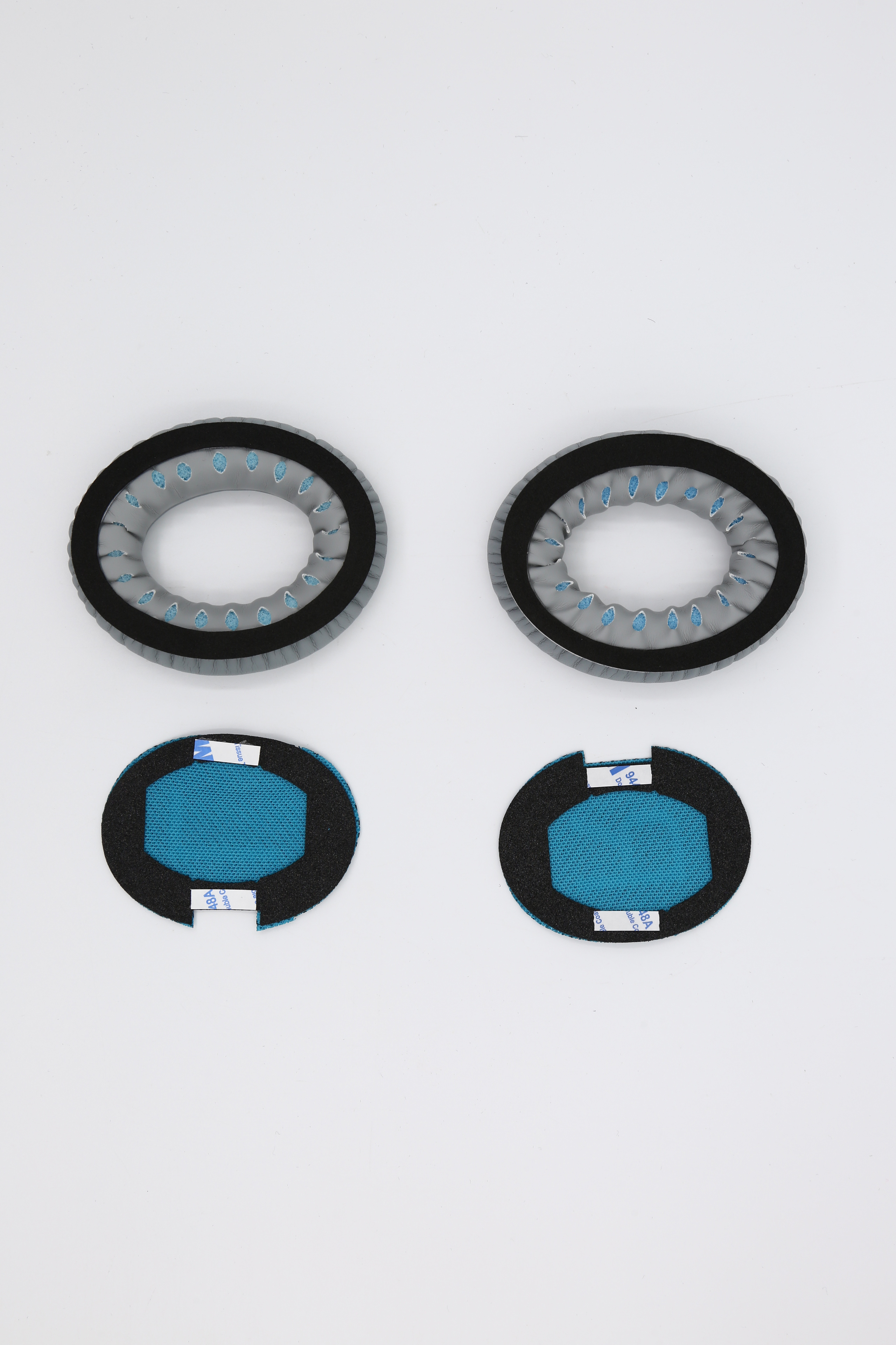 Dwie pary szarych i niebieskich nauszników do słuchawek, z czarnym obramowaniem.