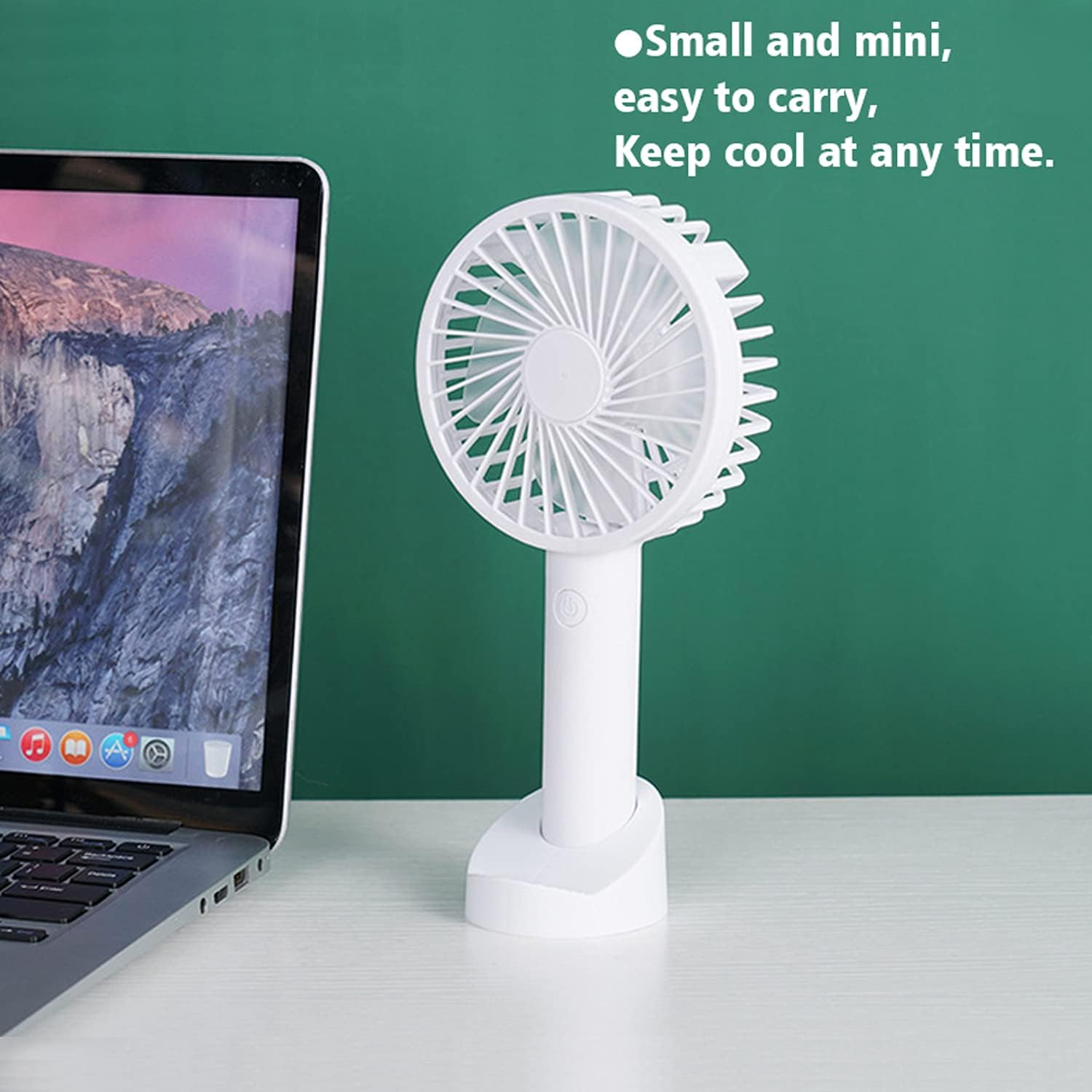Weißer tragbarer Ventilator auf einem Tisch neben einem Laptop. Der Hintergrund ist grün. Text oben.