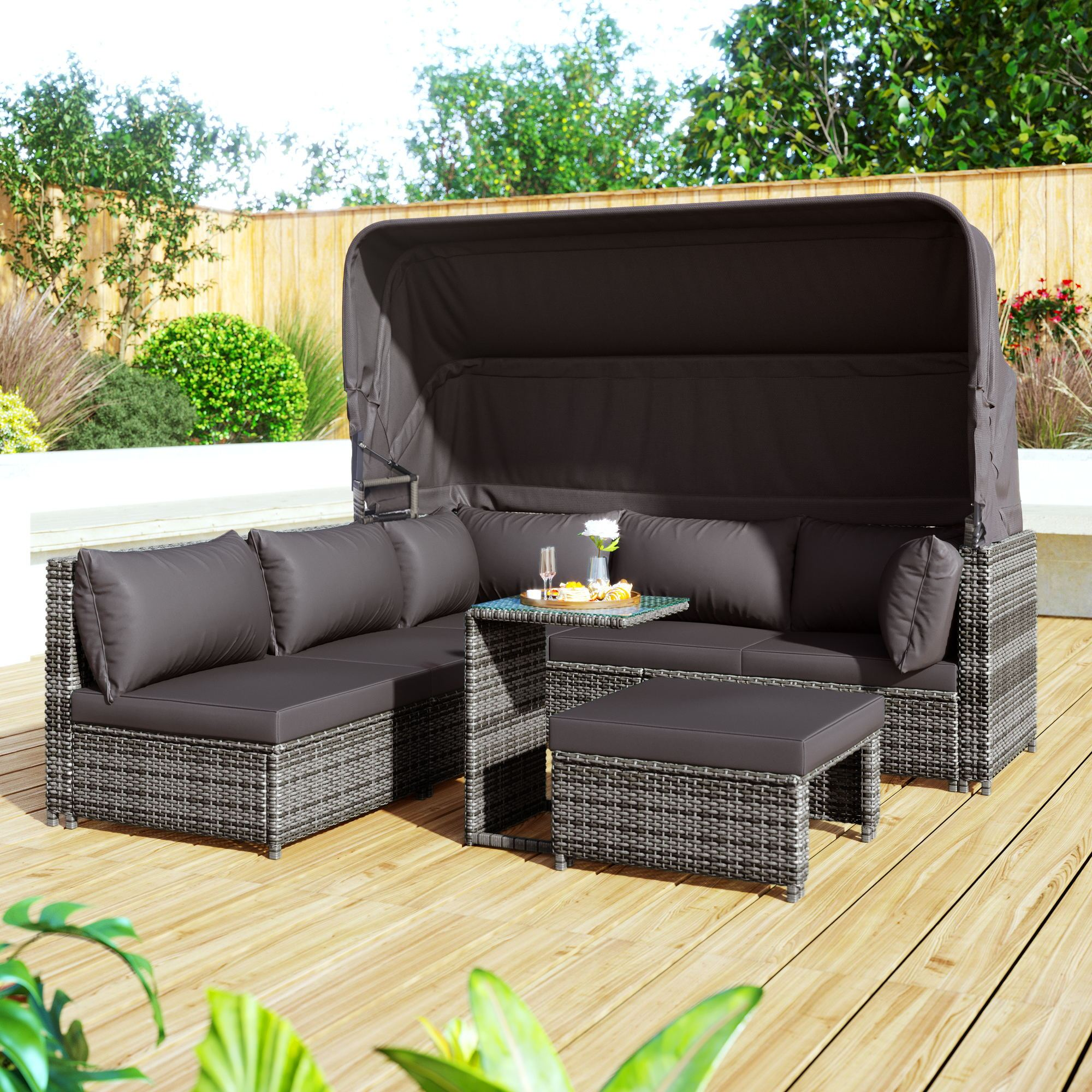 Graues Outdoor-Wicker-Sofaset mit Baldachin, Tisch und Ottoman auf Holzdeck.