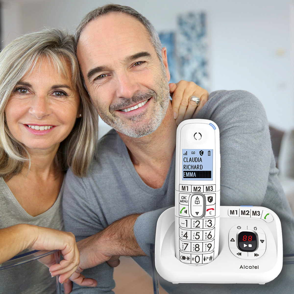 Een ouder echtpaar dat lacht terwijl ze een draadloze telefoon en de basis vasthouden.