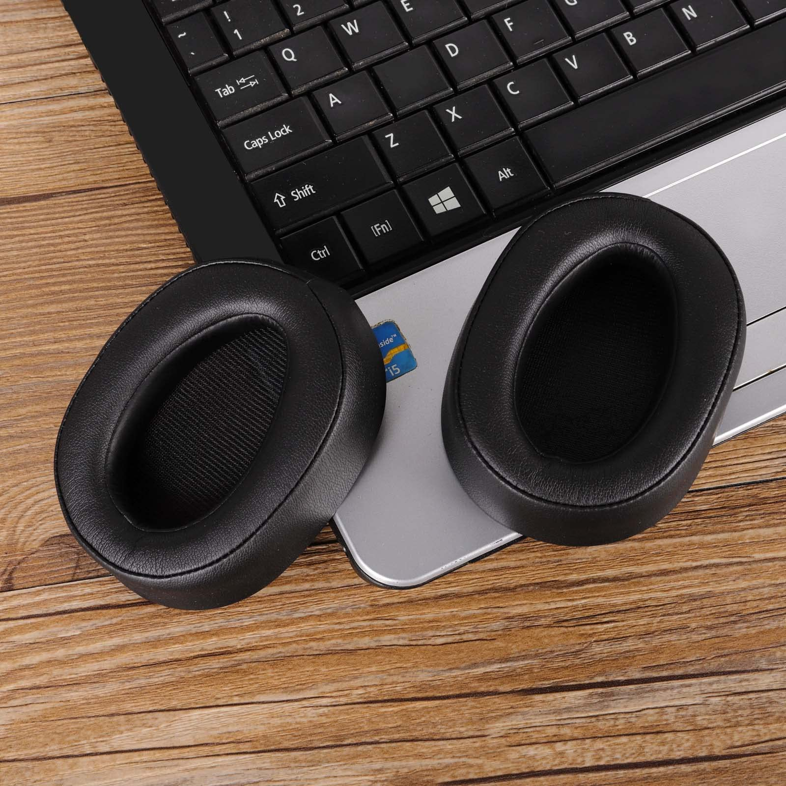 Deux coussinets d'oreille de casque noirs ovales sur un clavier d'ordinateur portable.