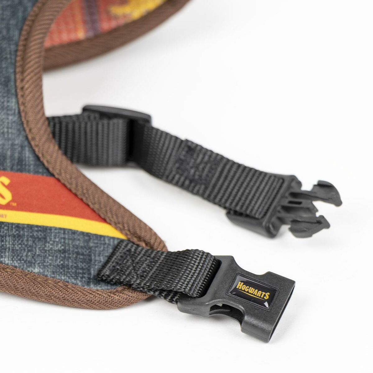 Hunde Geschirr Detail mit Schnallen. Das Geschirr ist aus Jeansstoff mit braunem Besatz. Das Wort "Hogwarts" ist sichtbar.