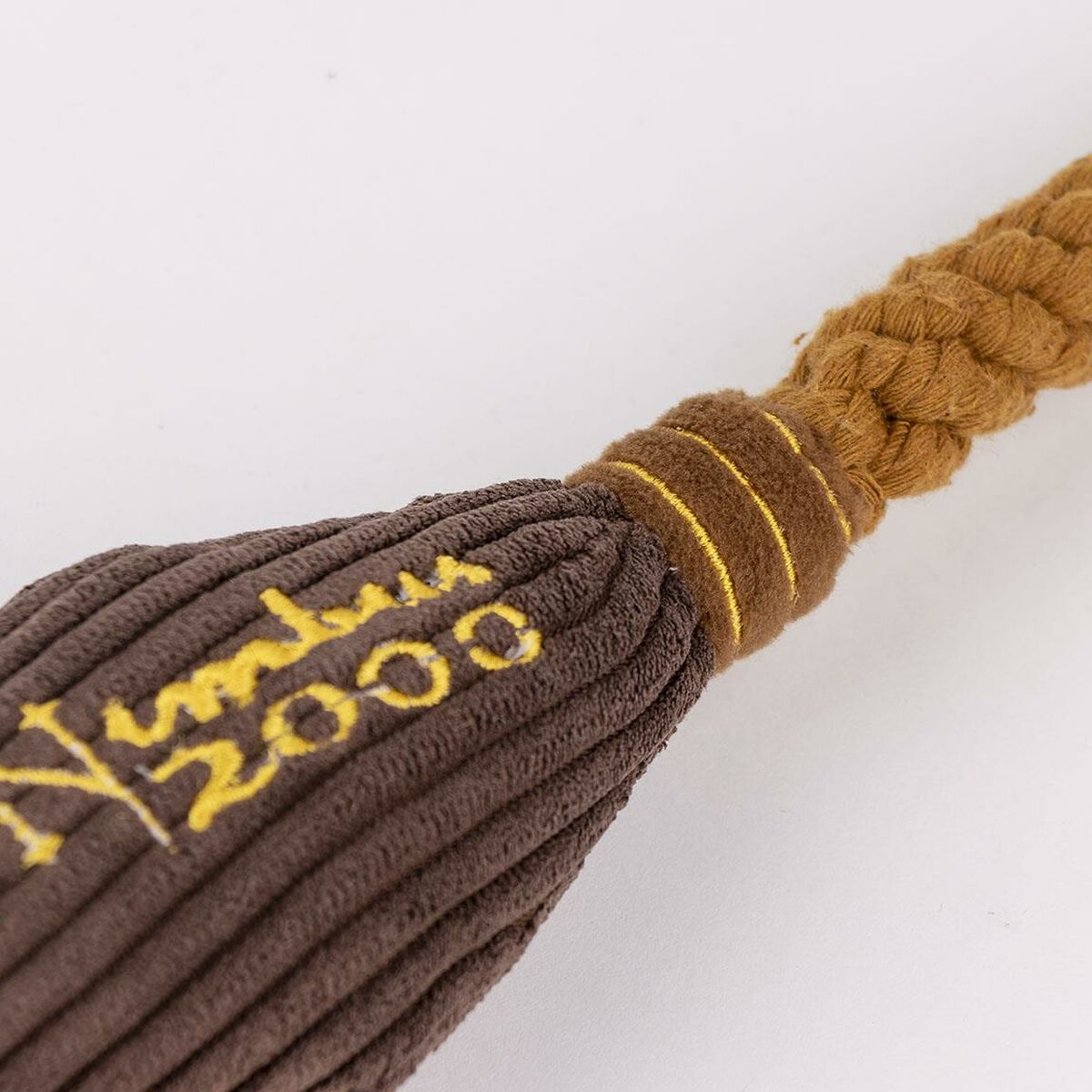Primo piano di un giocattolo per cani in velluto a coste marrone con testo giallo che dice "Nimbus 2000".