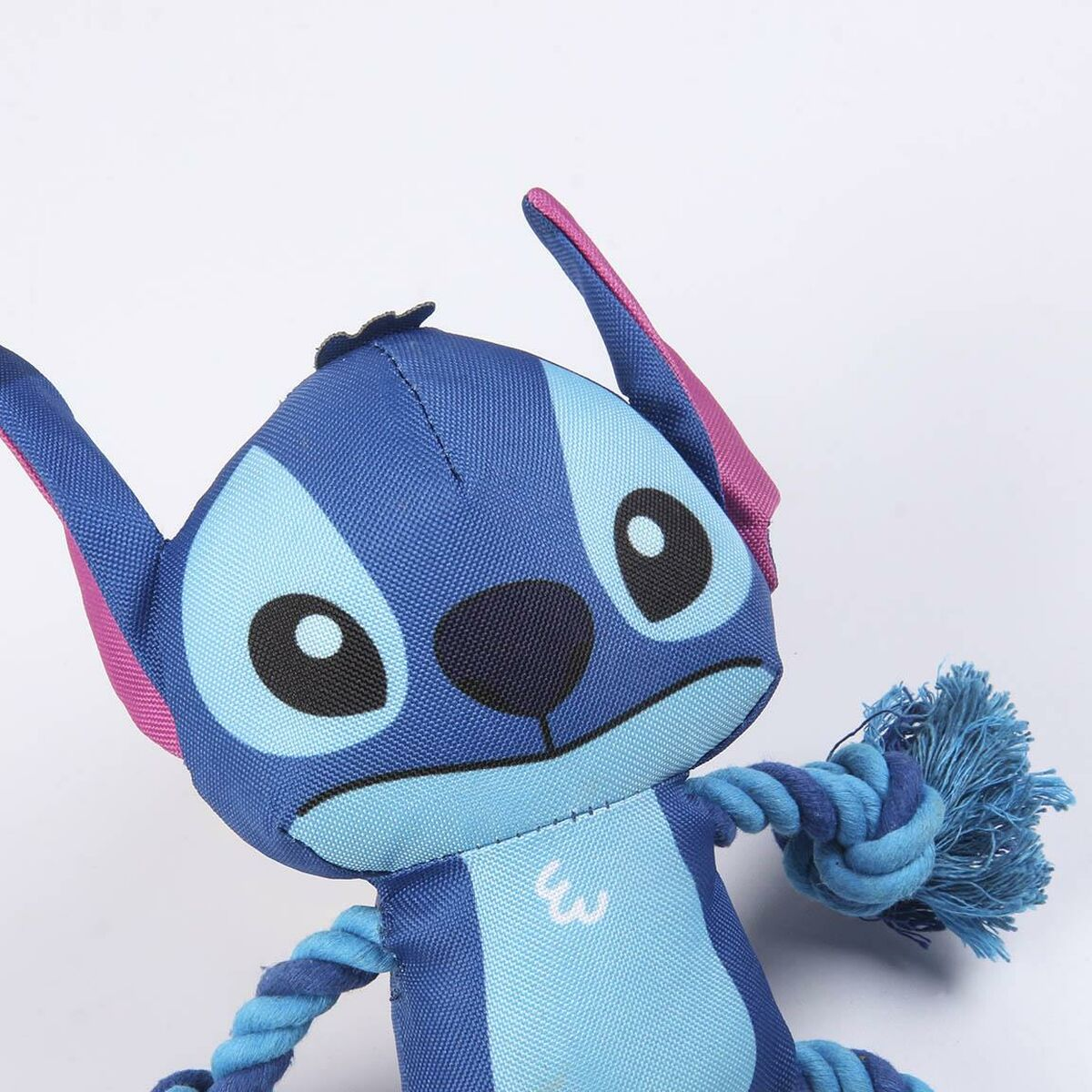 Primo piano di un peluche blu di Stitch che tiene una corda. Ha grandi occhi e un'espressione carina.