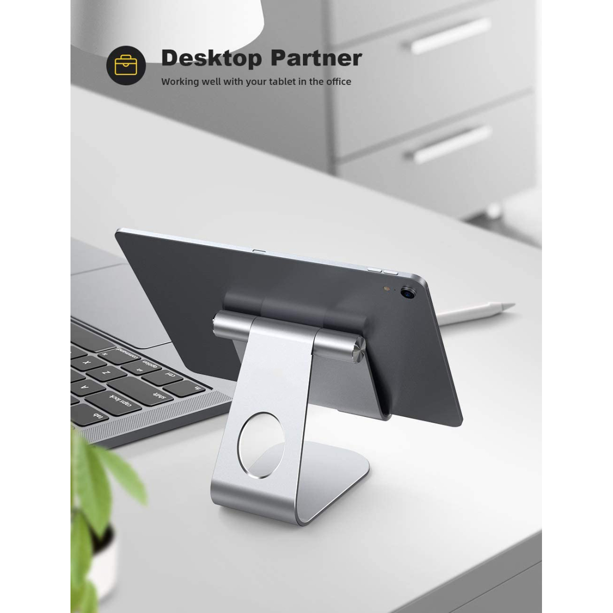 Ein silberner Tablet-Ständer mit einem Tablet darauf. Der Ständer steht auf einem Schreibtisch.
