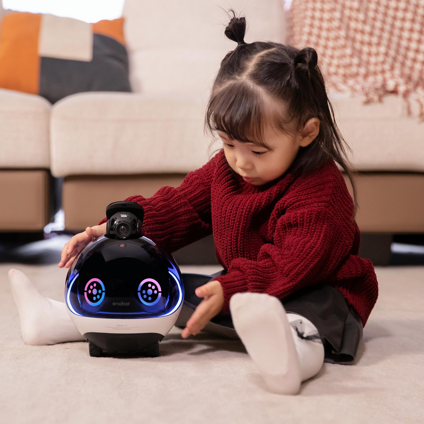 Un bambino che interagisce con un robot bianco e nero con luci.