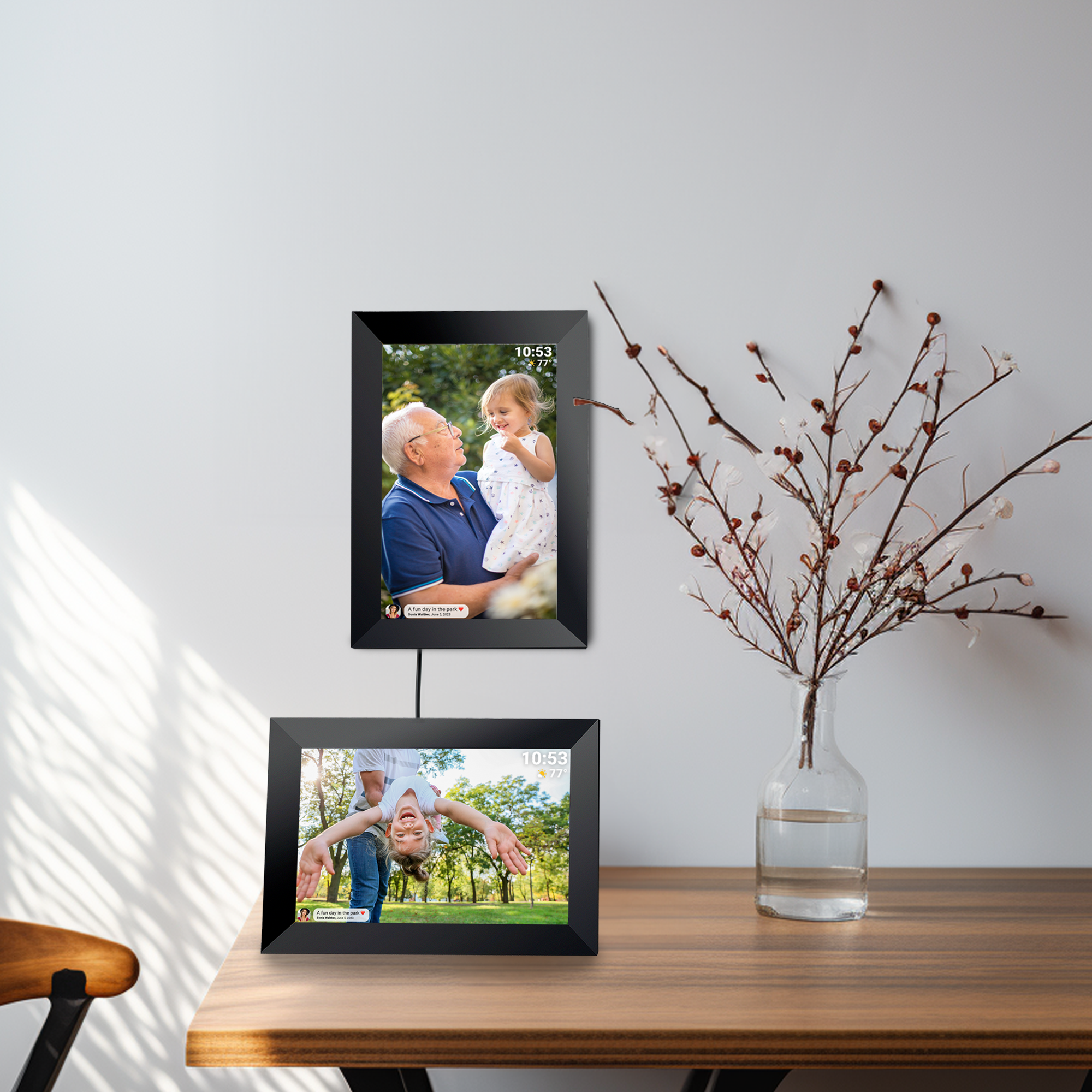 Dwie czarne cyfrowe ramki na zdjęcia na drewnianym stole. Jedna pokazuje dziadka i wnuczkę, a druga dziecko.