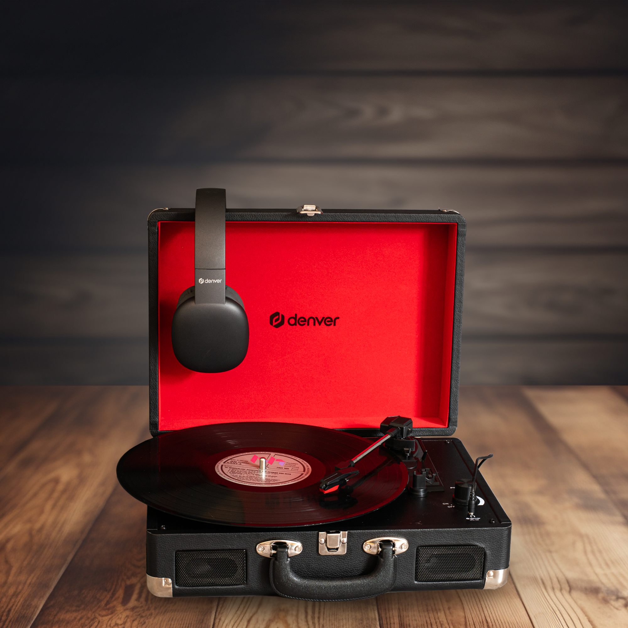 Gramofon ze słuchawkami w czerwonej walizce na drewnianej powierzchni.