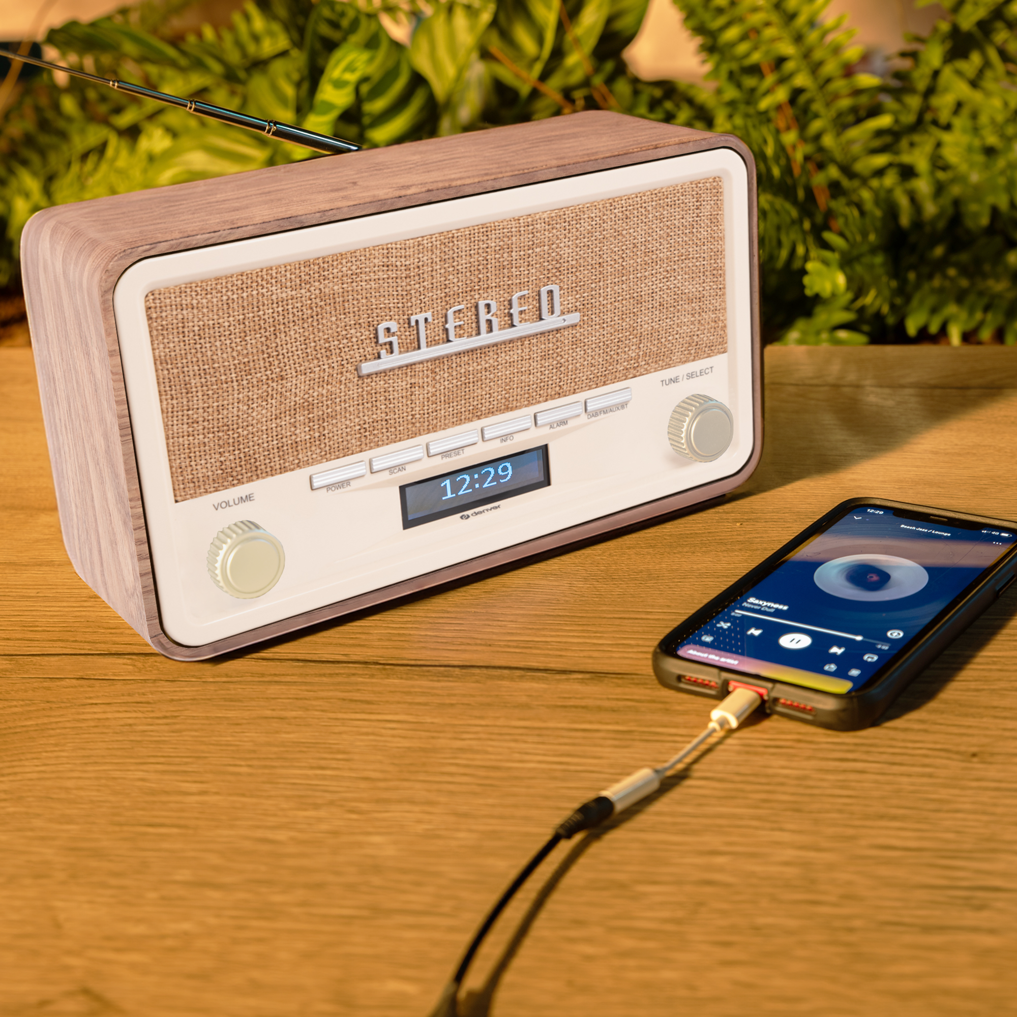 Wooden stereo radio with a phone attached. The phone is showing a music app.