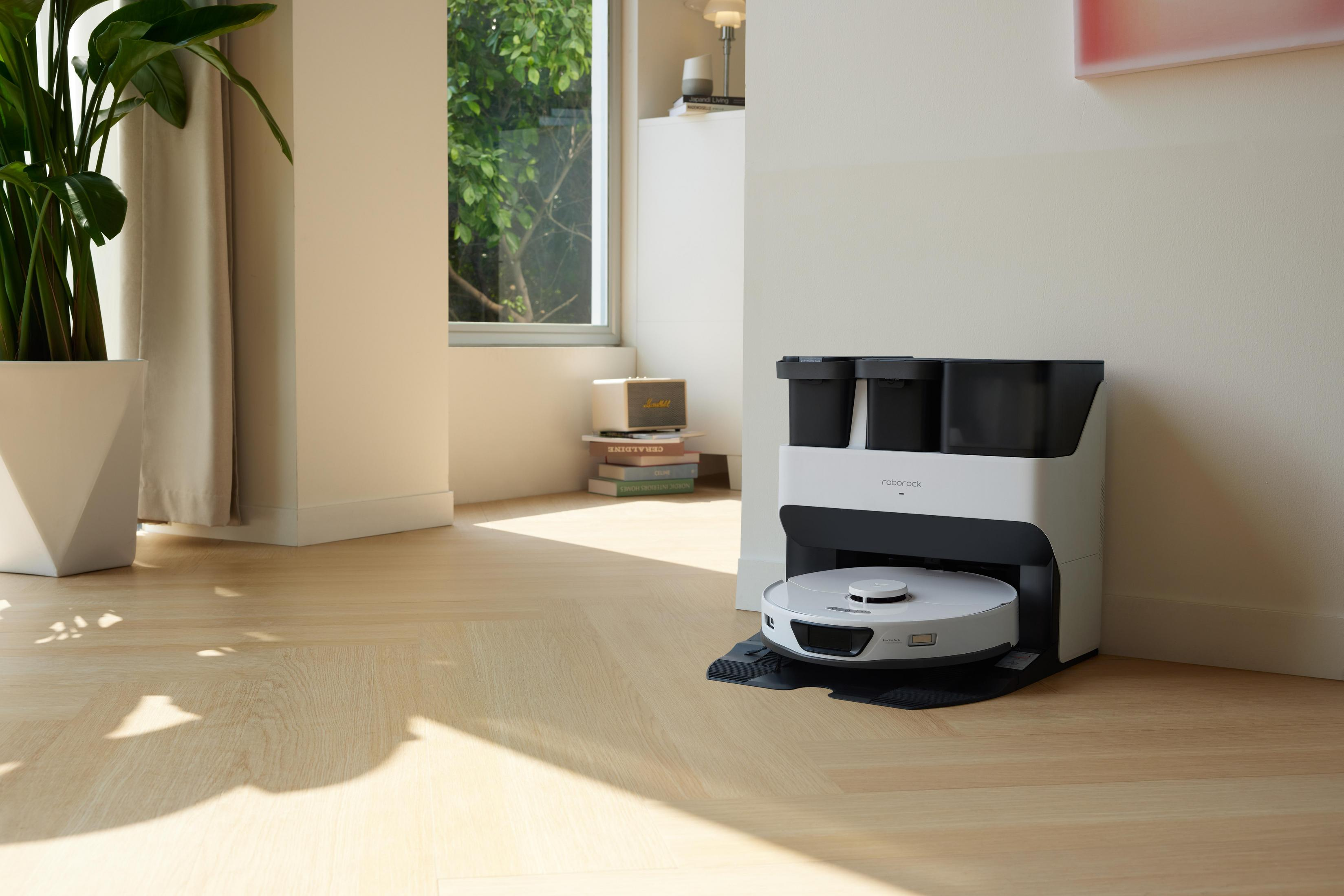 Roboter-Staubsauger auf Holzboden. Der Staubsauger befindet sich in der Nähe einer Ladestation in einem Raum.