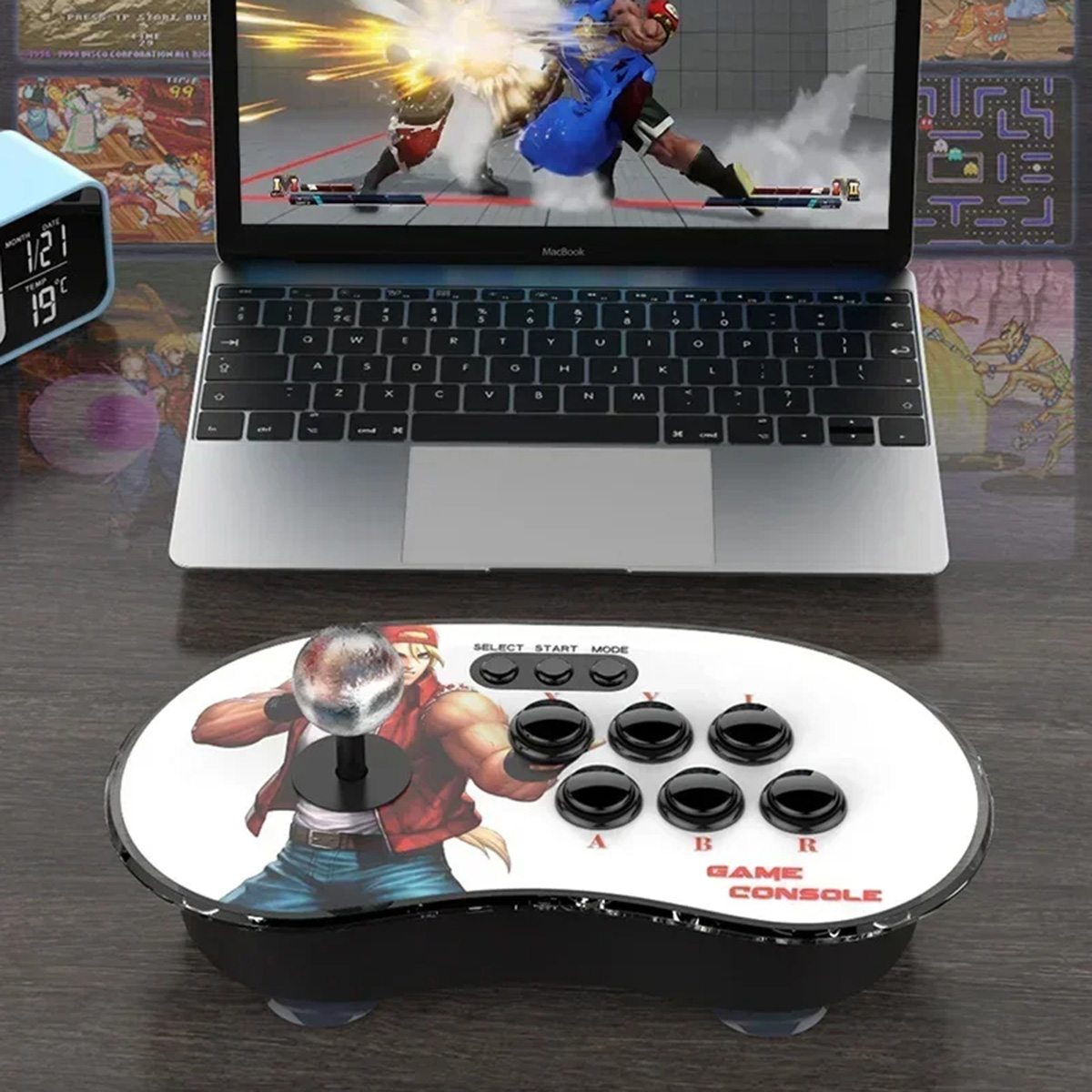 Una consola de juegos con un joystick, botones y un portátil que muestra un juego.