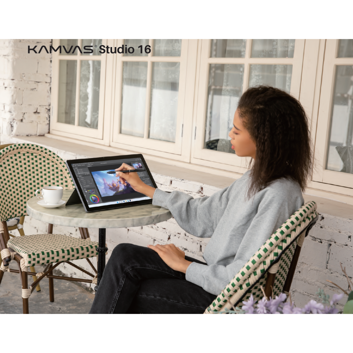 Osoba używa tabletu z piórem na zewnątrz. Na stole stoi filiżanka kawy.