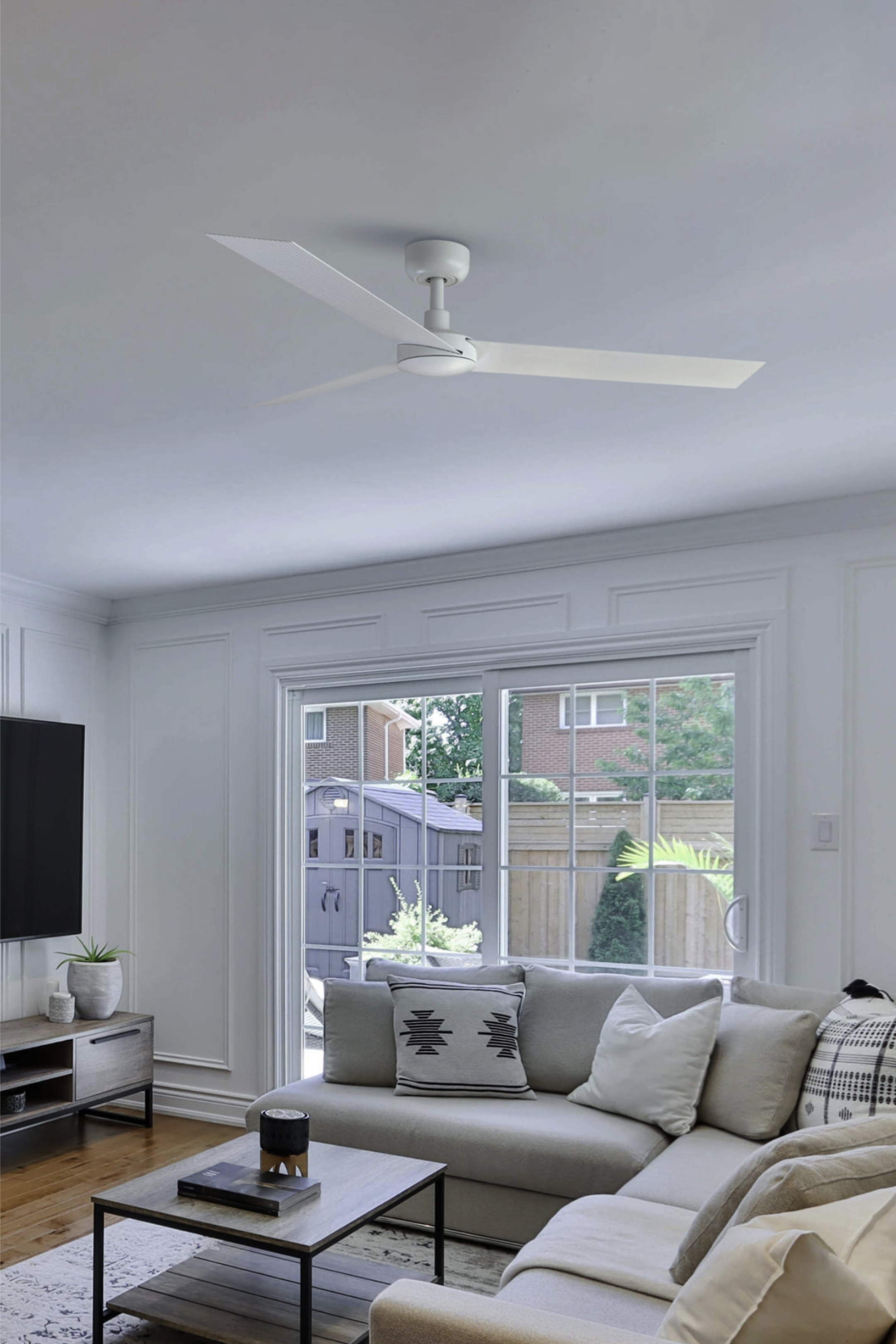 Wohnzimmer-Interieur mit weißem Deckenventilator. Weiße Wände und ein großes Fenster.