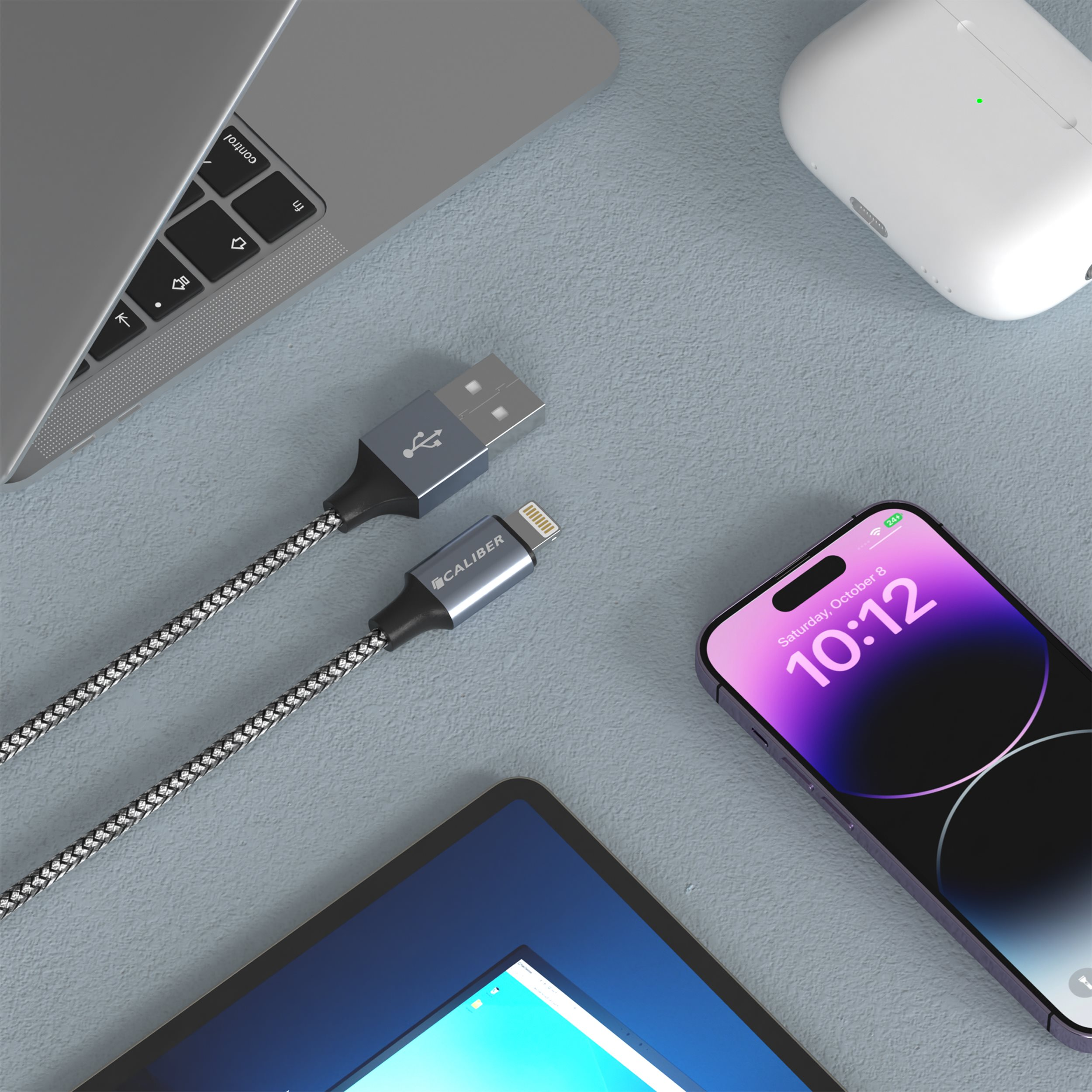 USB-Kabel, Tablet, Telefon und AirPods auf grauer Oberfläche.